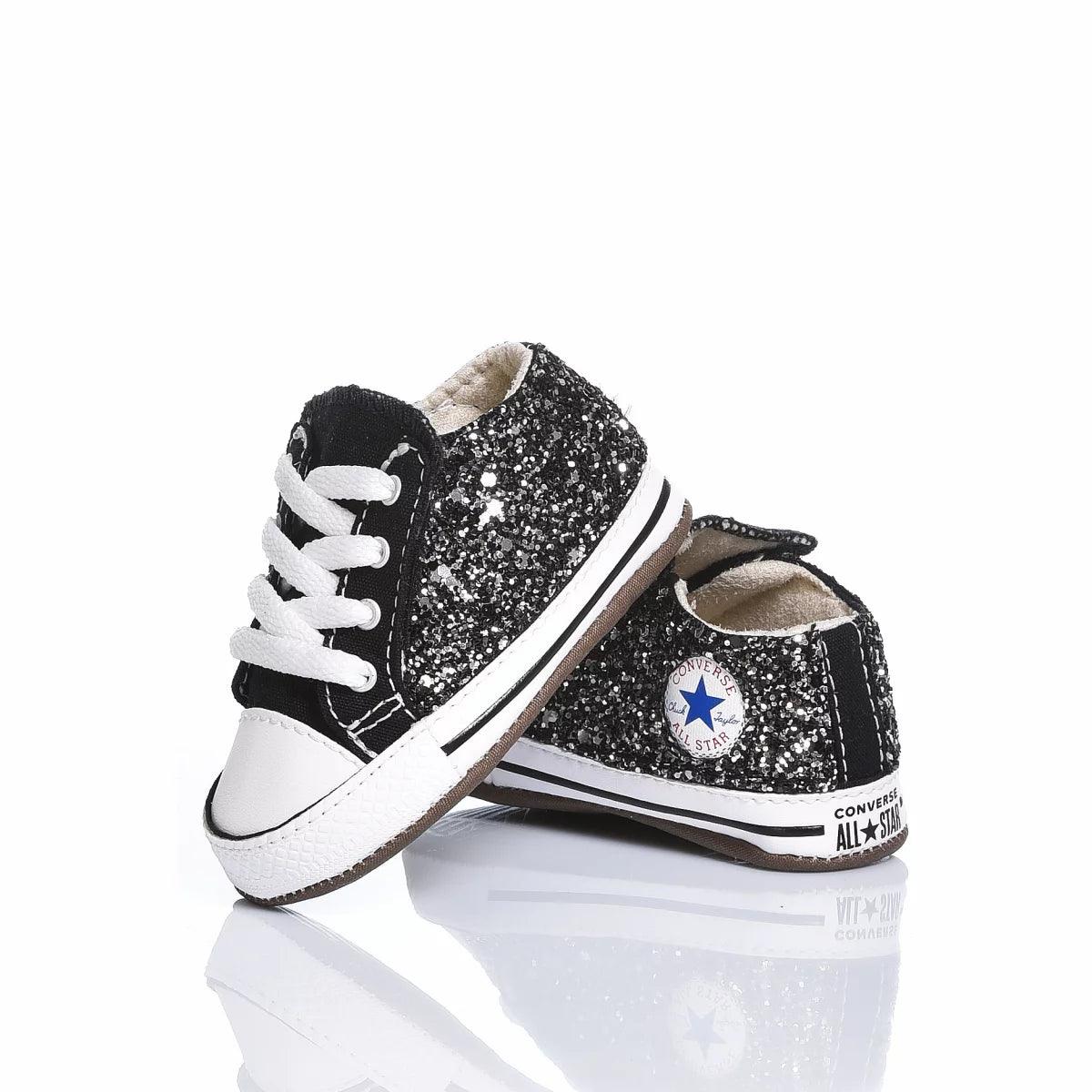 Scarpe baby nere glitterate ideali per outfit premaman e moda neonato, fondo bianco.