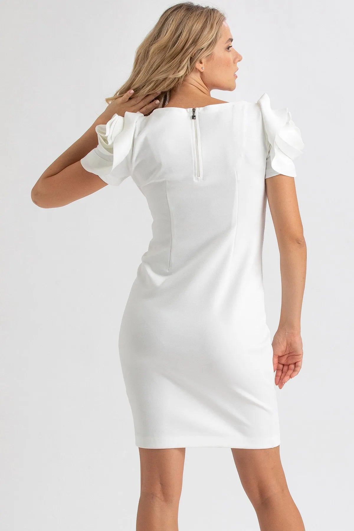 Abito premaman bianco elegante con maniche a balze, visto da dietro su sfondo neutro.