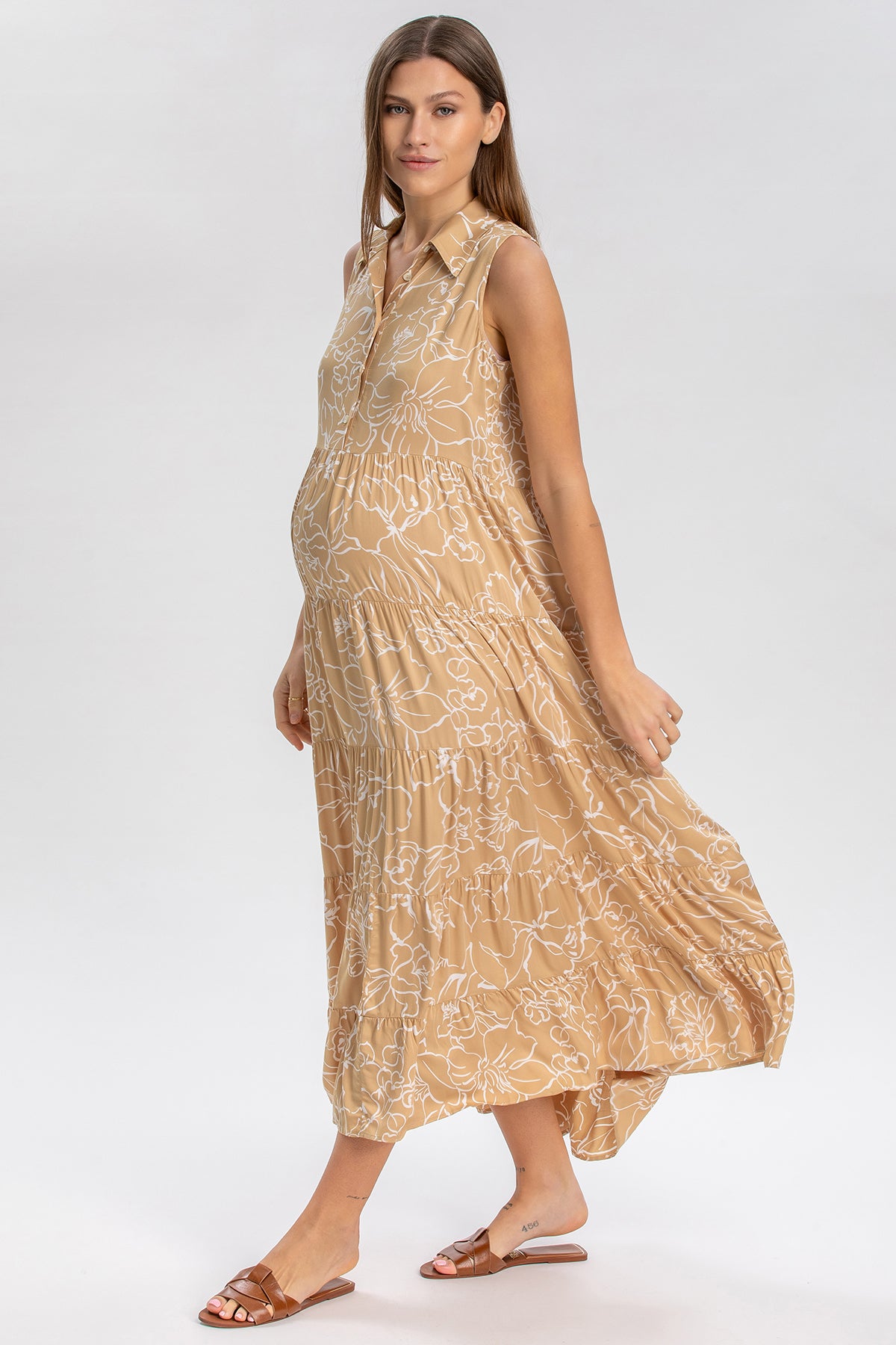 Abito premaman lungo senza maniche beige con fantasia floreale, indossato da una donna incinta.