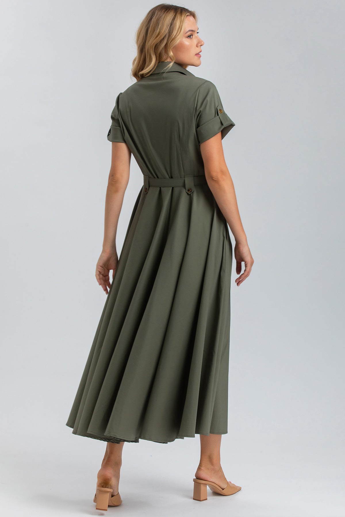 Donna di profilo indossa abito premaman verde lungo, maniche corte, sandali beige