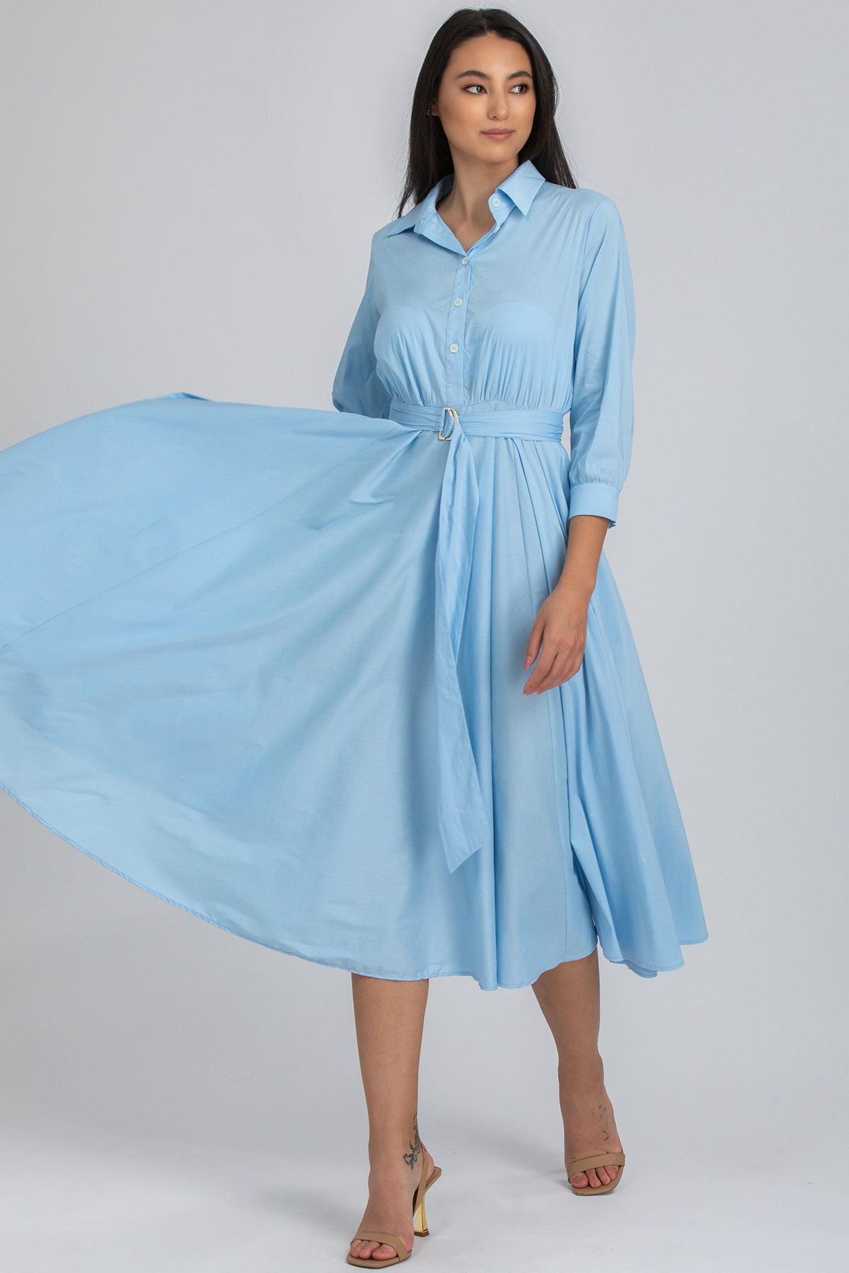 Donna con abito premaman azzurro a maniche lunghe, vita alta e gonna svasata elegante