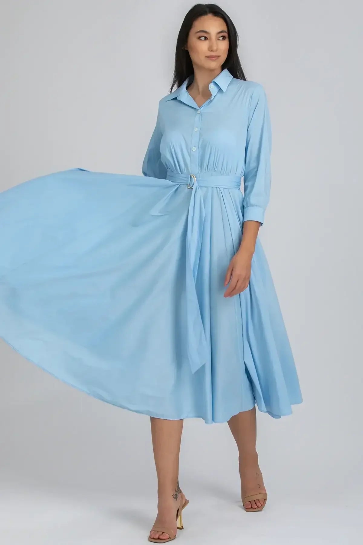 Donna con abito premaman azzurro a maniche lunghe, vita alta e gonna svasata elegante