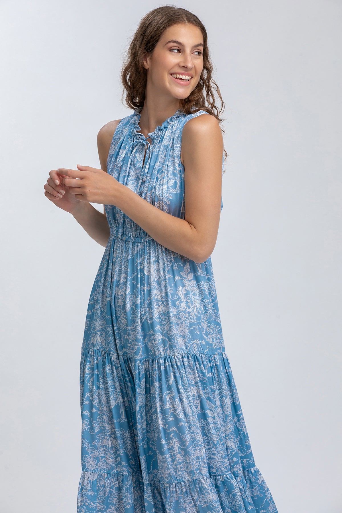 Vestito premaman lungo azzurro senza maniche con stampa floreale, donna sorridente.