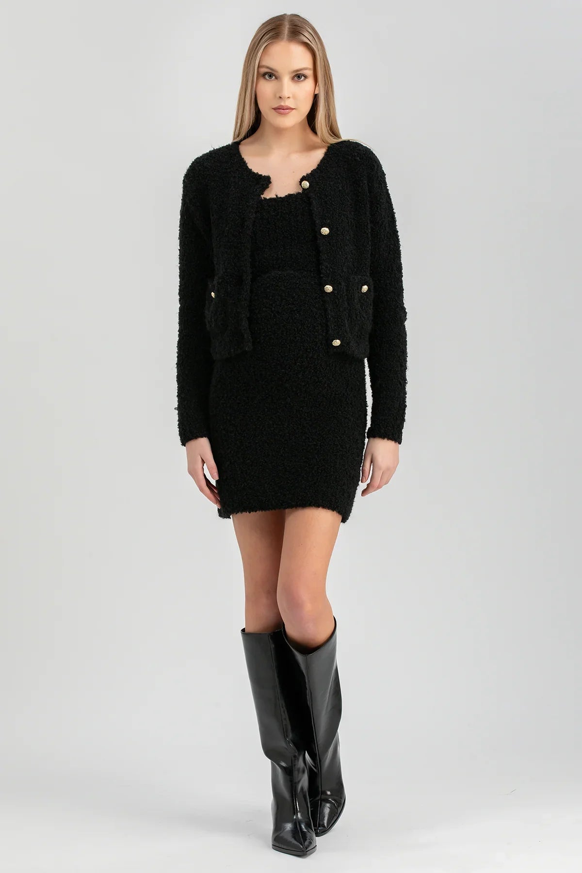 Donna indossa completo premaman nero in maglia boucle con giacca corta e stivali alti neri