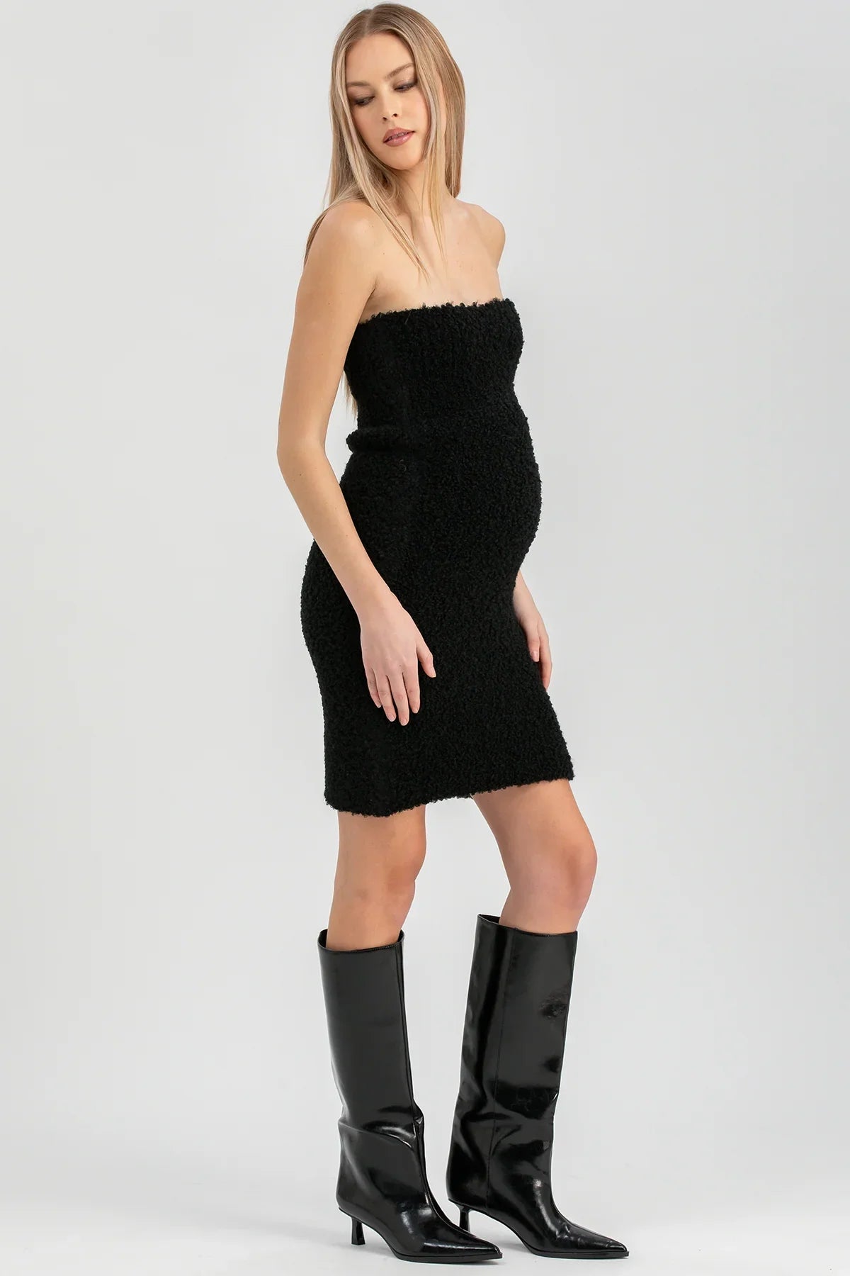 Donna in abito nero senza spalline e stivali alti neri, moda elegante premaman