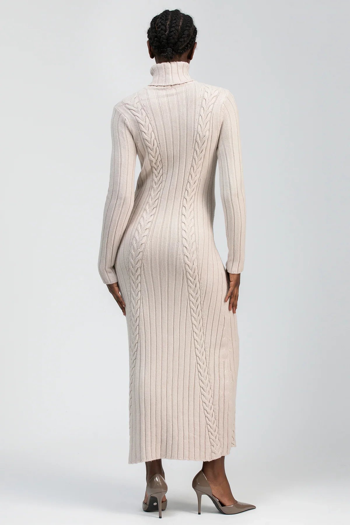 Abito premaman lungo in maglia beige, collo alto, lavorazione a trecce, indossato da donna.