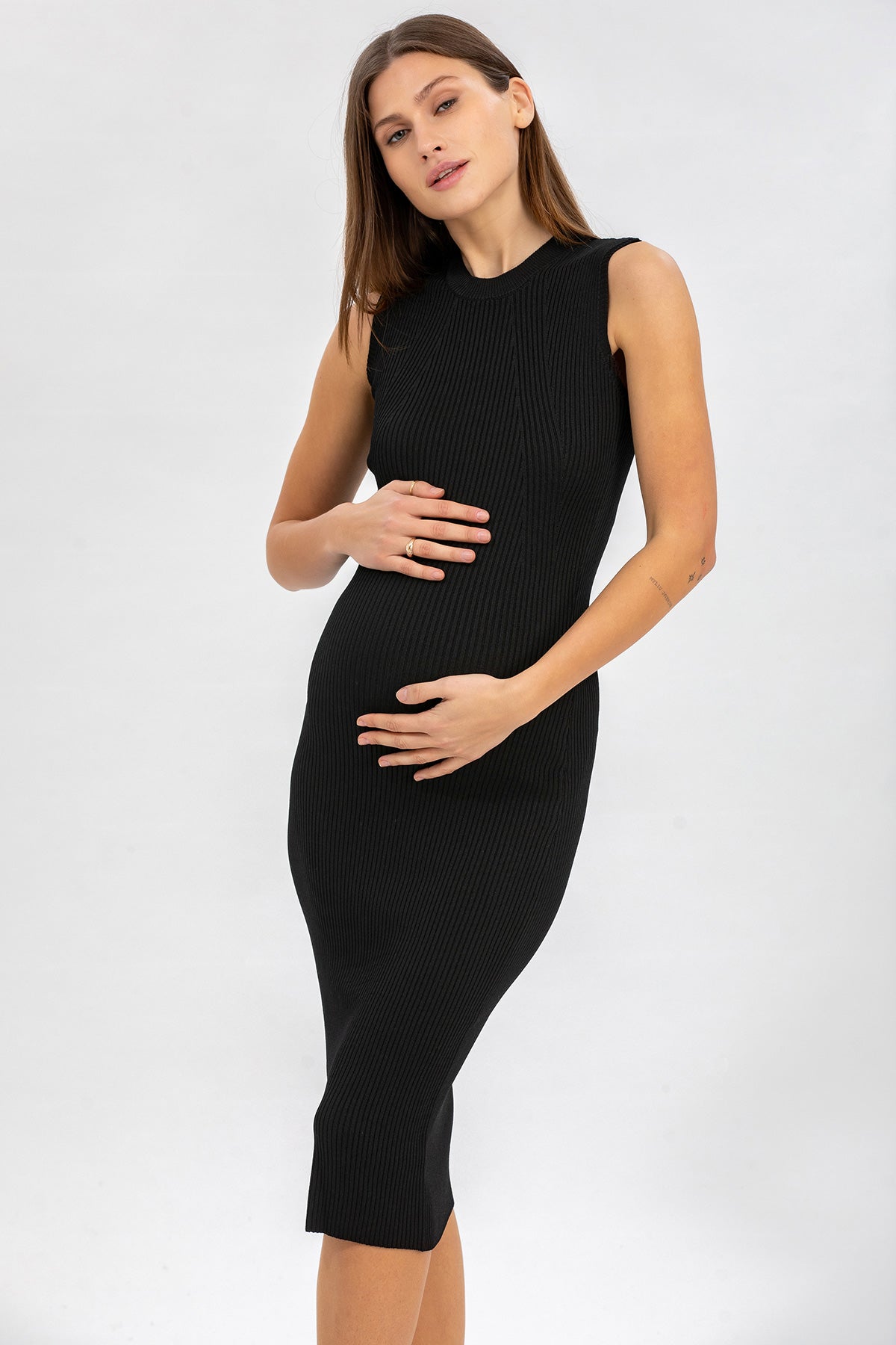 Donna incinta con abito premaman nero senza maniche in maglia, sfondo neutro