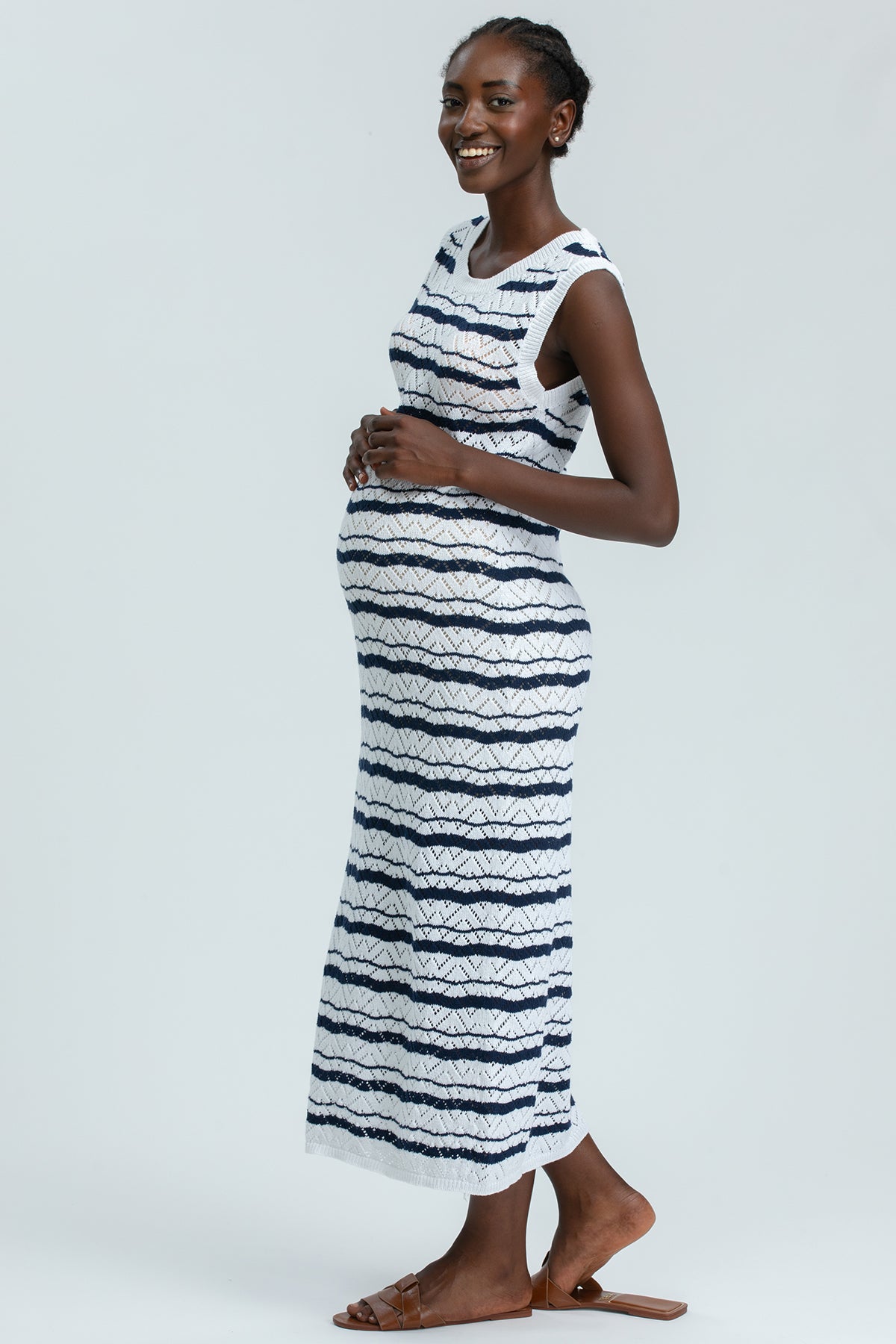 Modella incinta con abito premaman lungo bianco e blu a righe, look estivo elegante