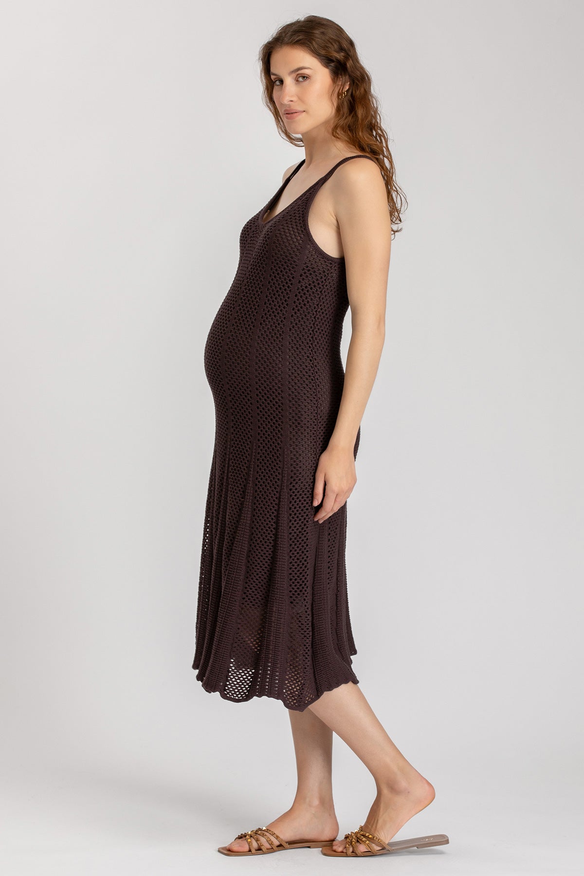Vestito premaman estivo in maglia traforata marrone, donna incinta in piedi su sfondo neutro