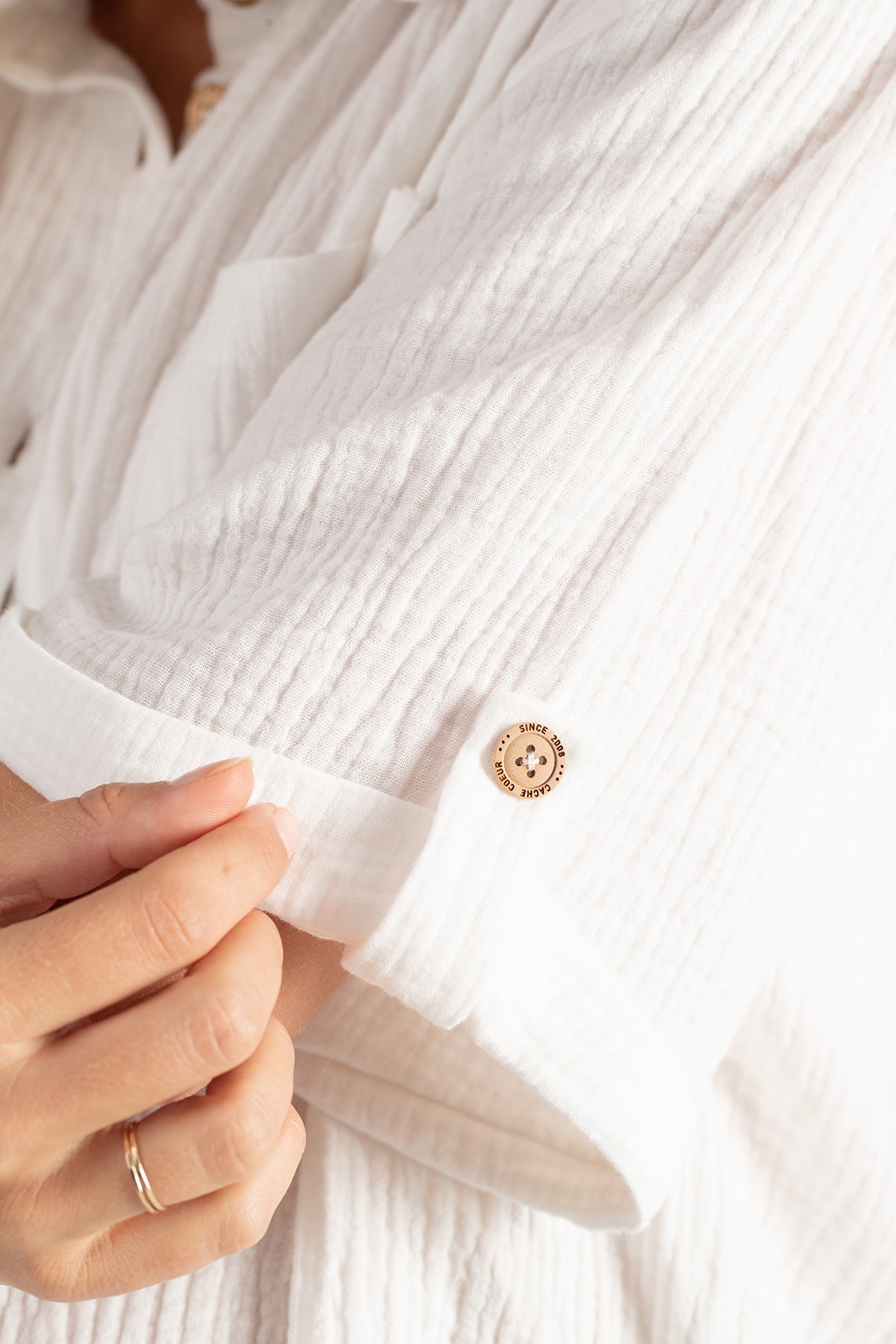 Dettaglio manica camicia premaman bianca in cotone, tessuto leggero e bottone chiaro