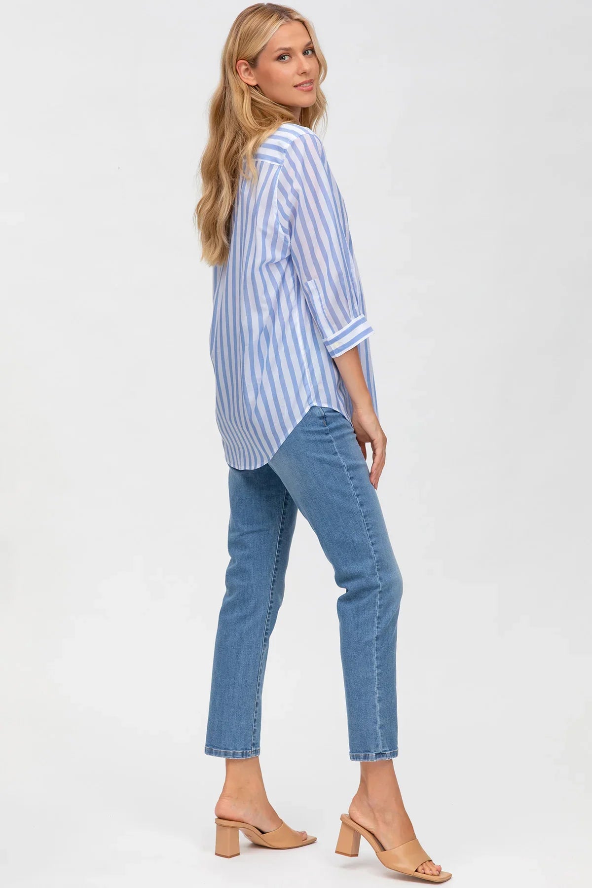 Donna incinta indossa camicia premaman a righe azzurre e pantaloni jeans, vista posteriore.