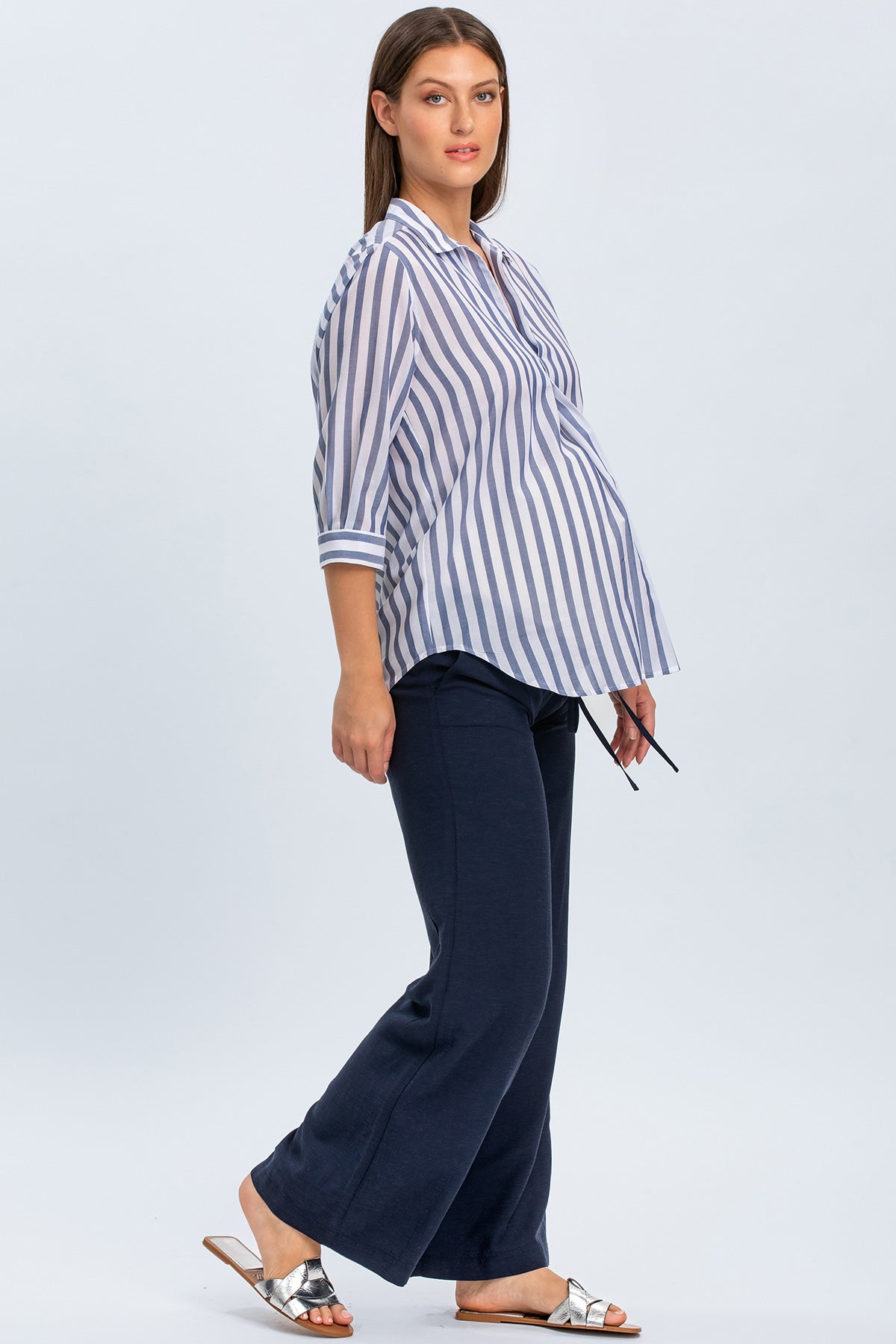 Donna incinta con camicia premaman a righe blu e bianche e pantaloni blu scuri