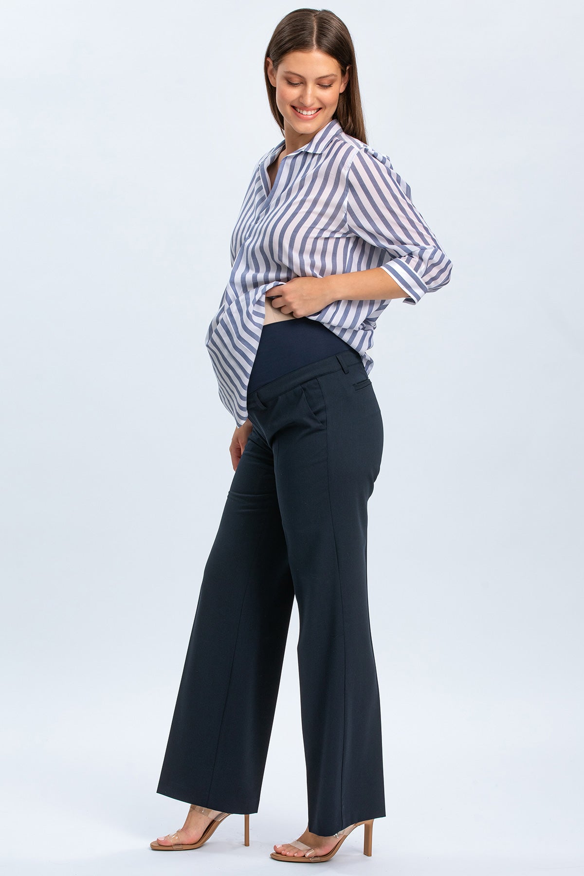 Donna incinta con camicia a righe e pantaloni premaman eleganti blu scuro