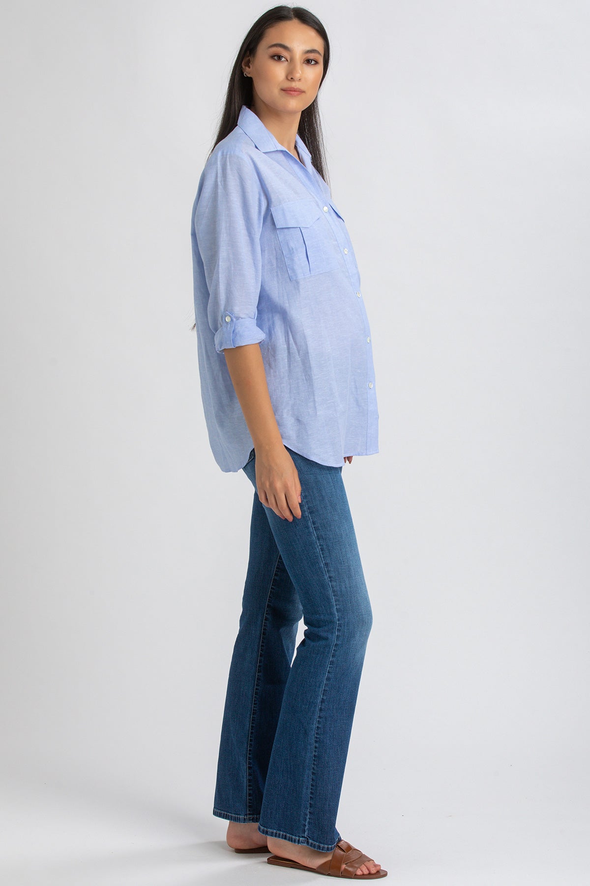 Donna incinta con camicia premaman azzurra e jeans flare, look casual elegante