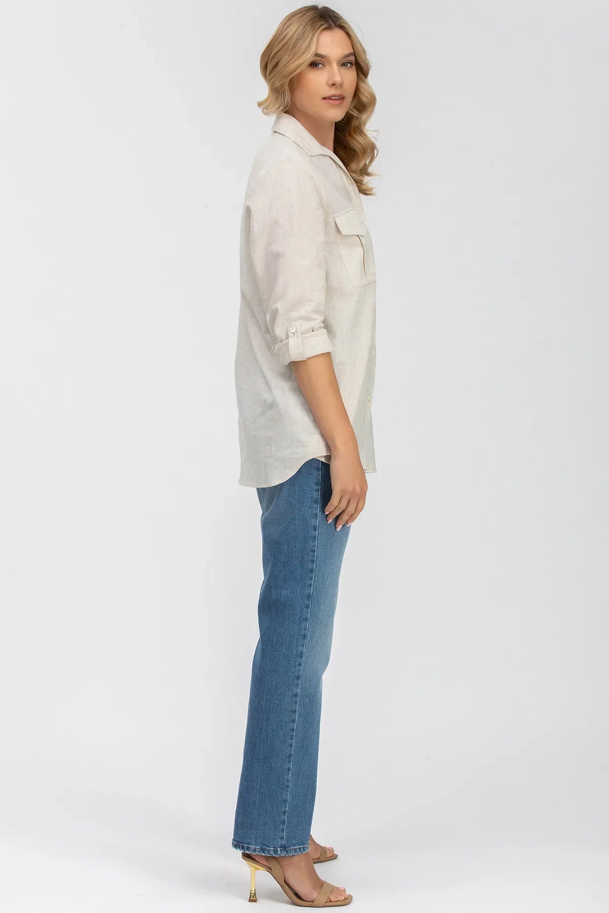 Donna incinta con camicia safari beige a maniche lunghe e jeans premaman su sfondo bianco