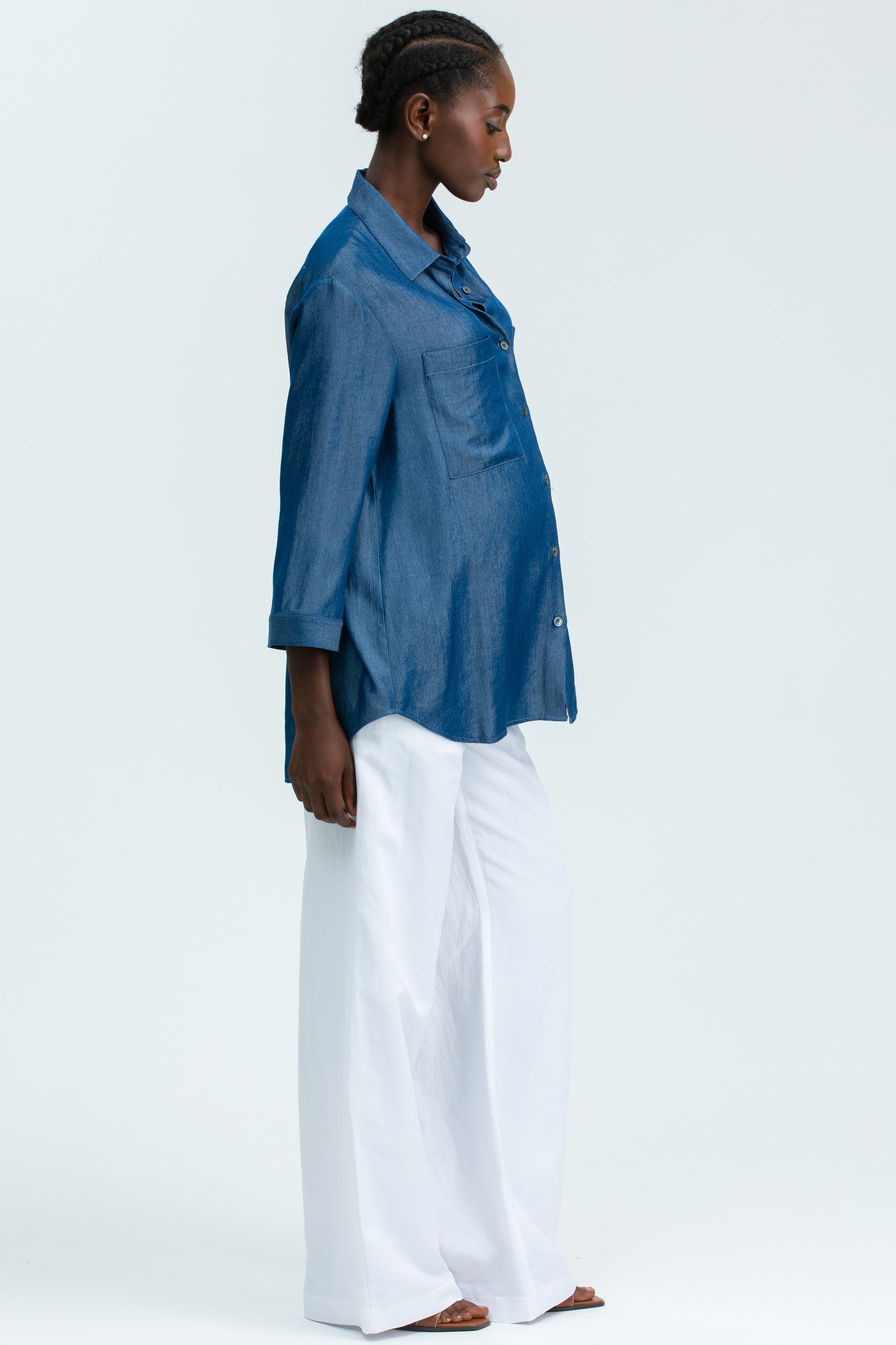 Modella premaman con camicia denim blu e pantaloni larghi bianchi, stile elegante