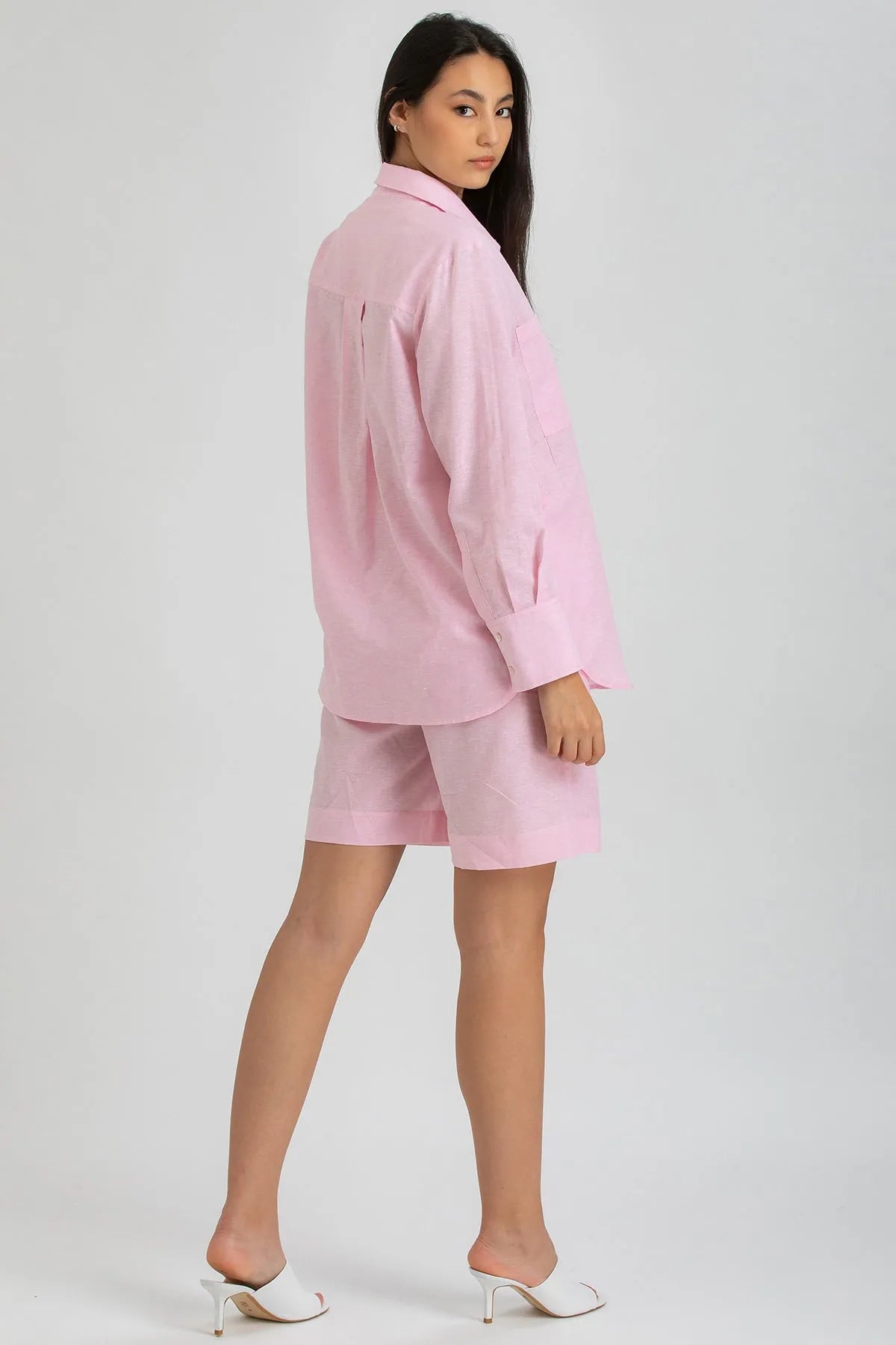 Modella con camicia oversize e shorts premaman rosa in lino, look elegante e confortevole.
