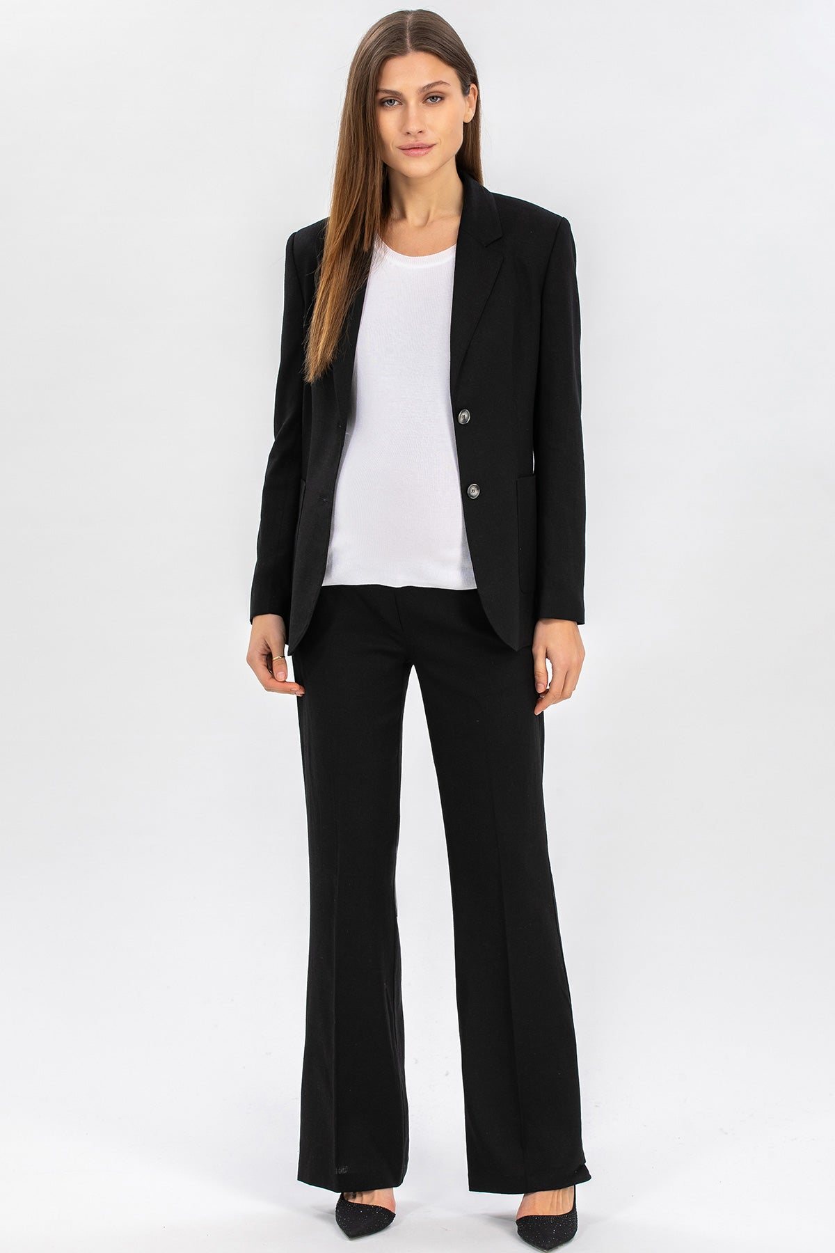 Completo premaman donna elegante con giacca e pantaloni neri, top bianco, su sfondo neutro