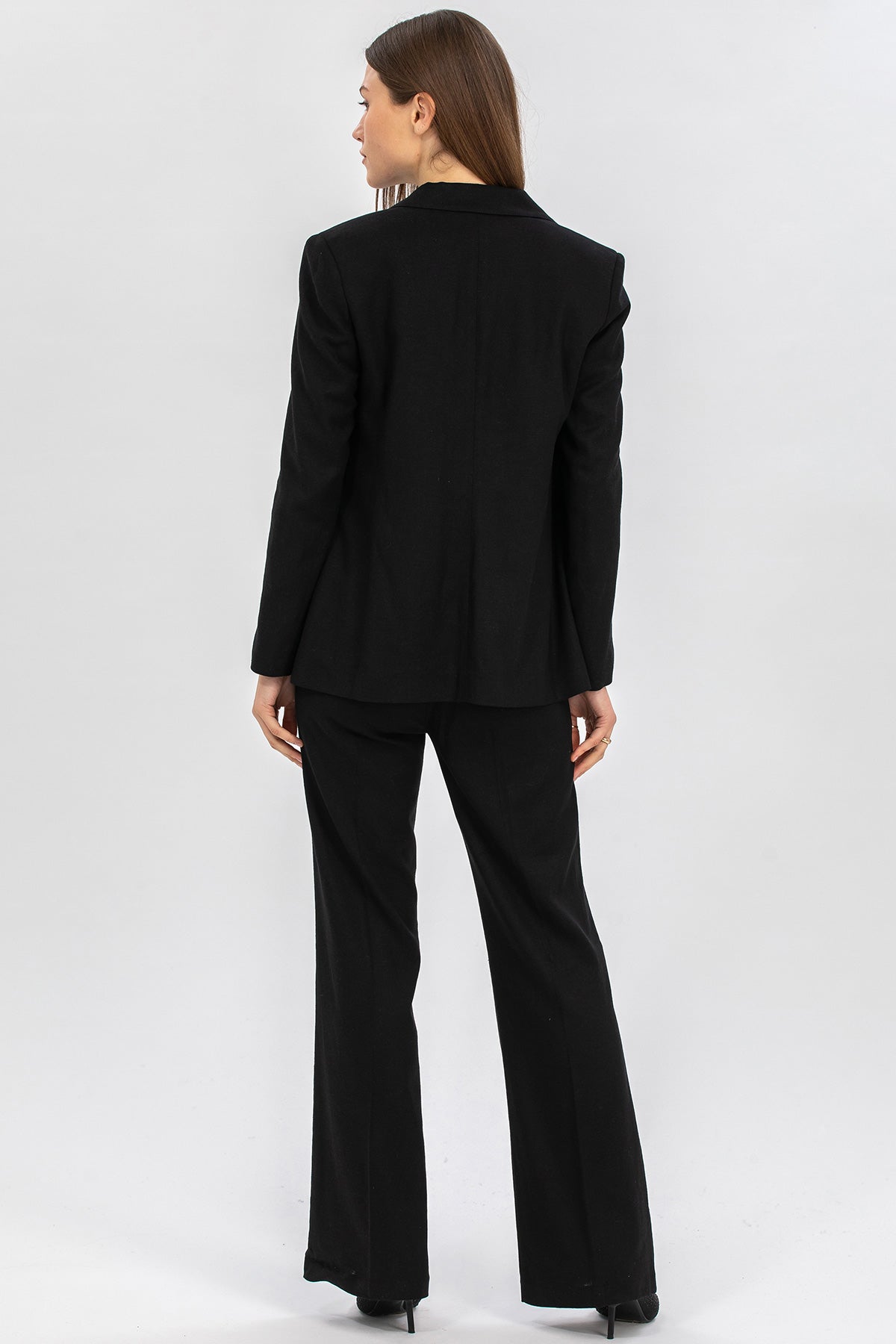 Donna in tailleur premaman nero elegante vista posteriore su sfondo neutro