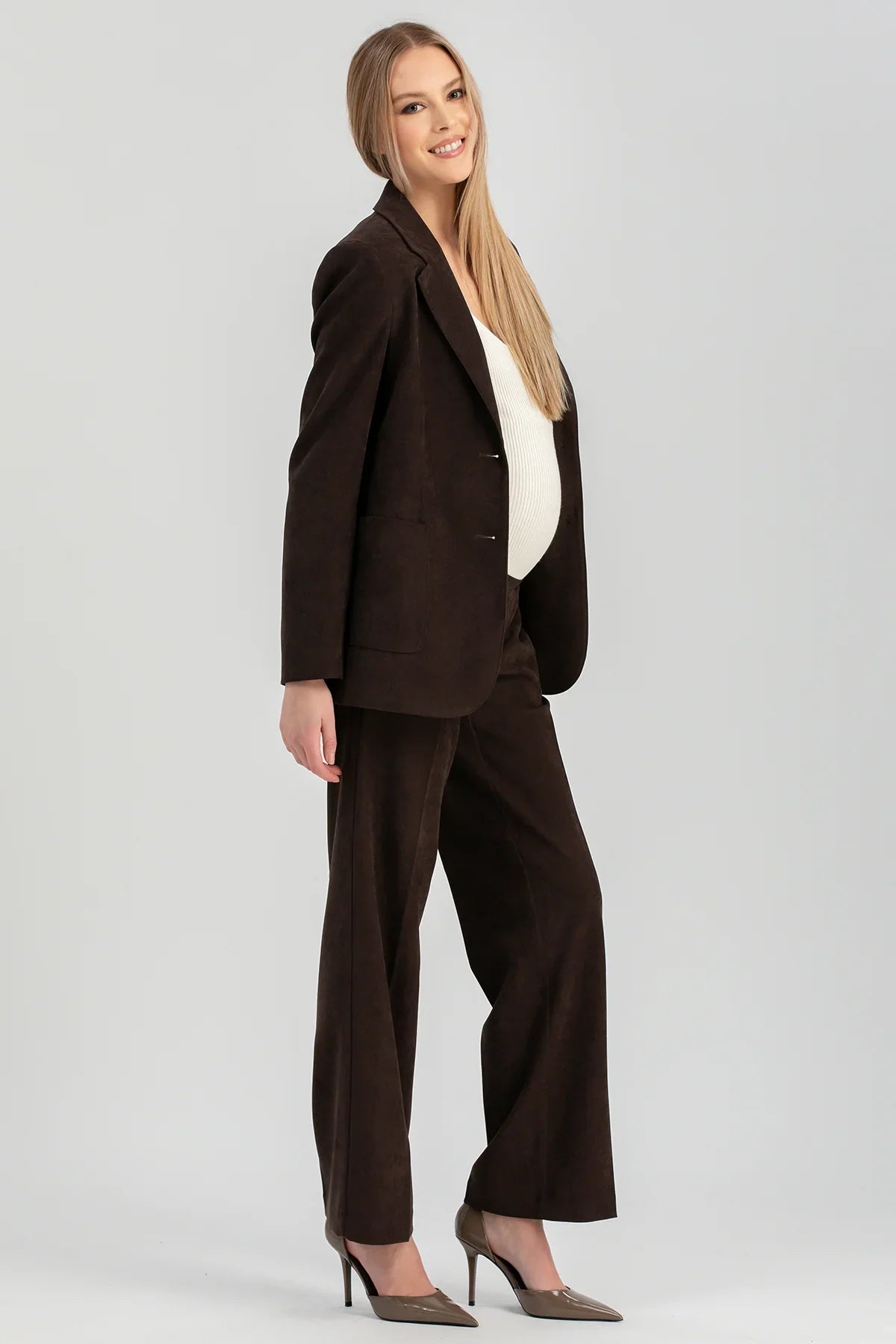 Donna con completo premaman marrone in velluto di Pietro Brunelli Maternity, gồm blazer e pantaloni premaman.