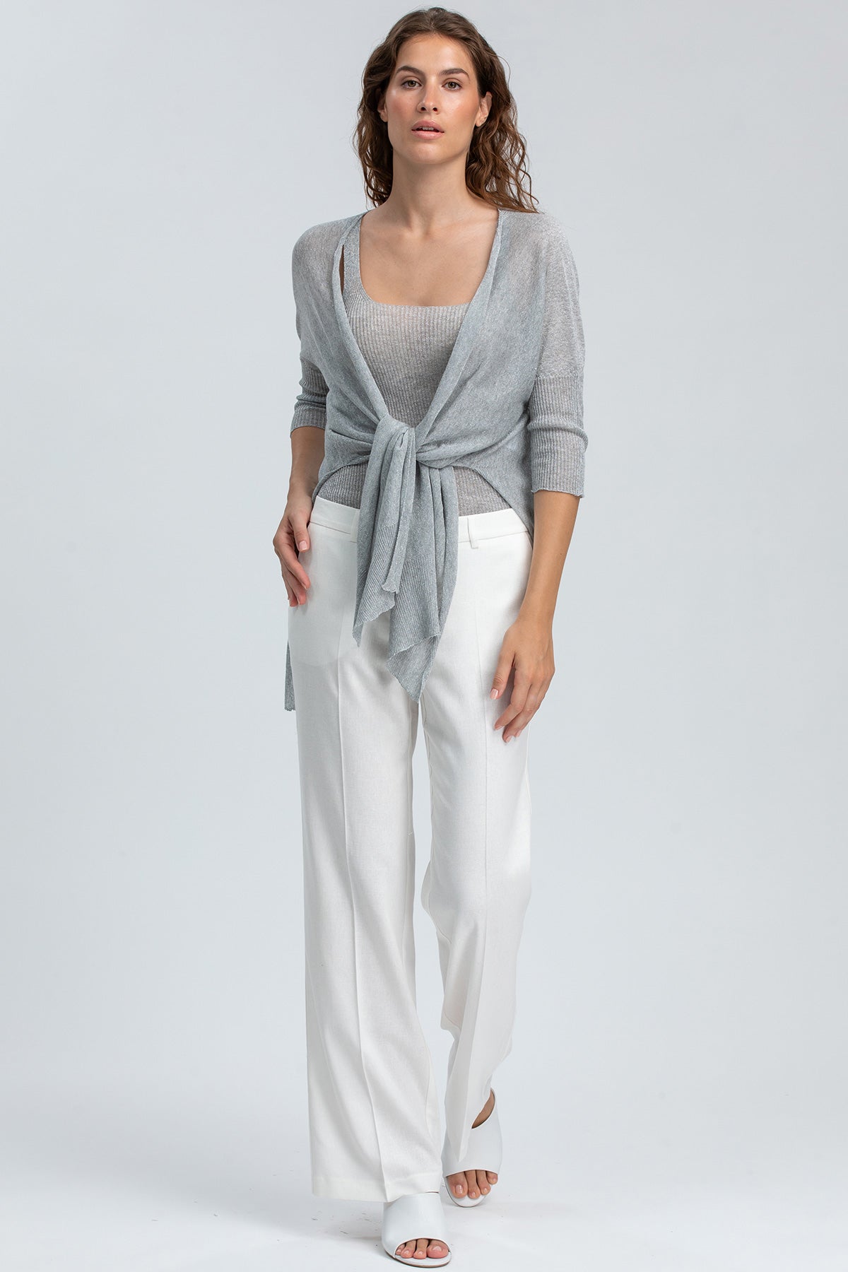 Modella indossa maglia e pantaloni bianchi premaman eleganti, look abbigliamento premaman.