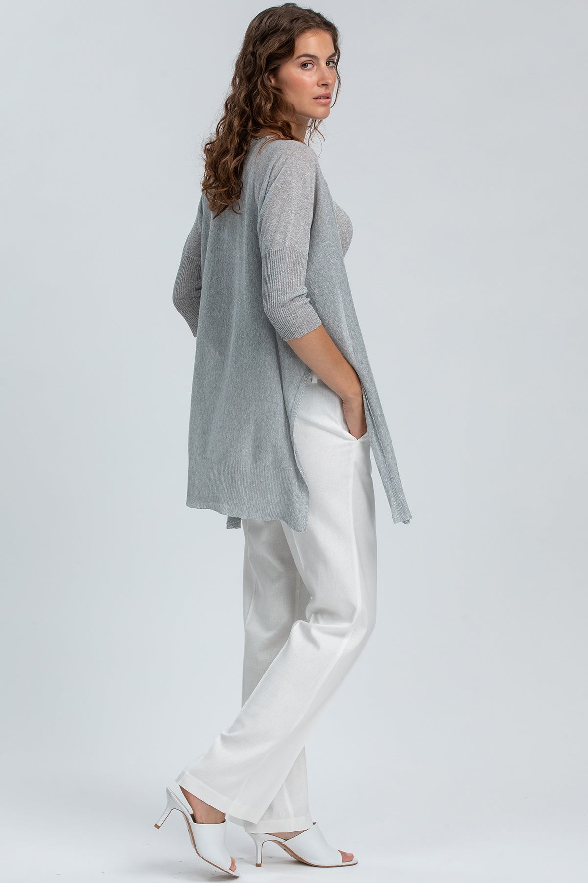 Donna che indossa cardigan premaman grigio e pantaloni bianchi eleganti
