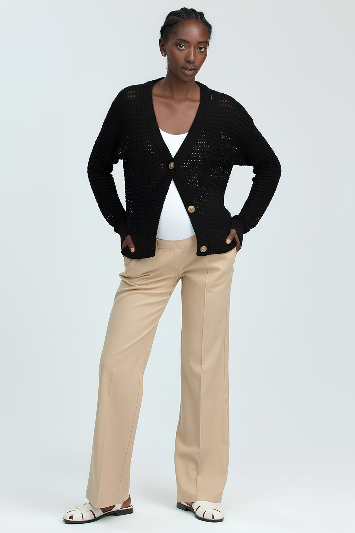 Donna che indossa cardigan nero e pantaloni beige premaman eleganti, moda premaman