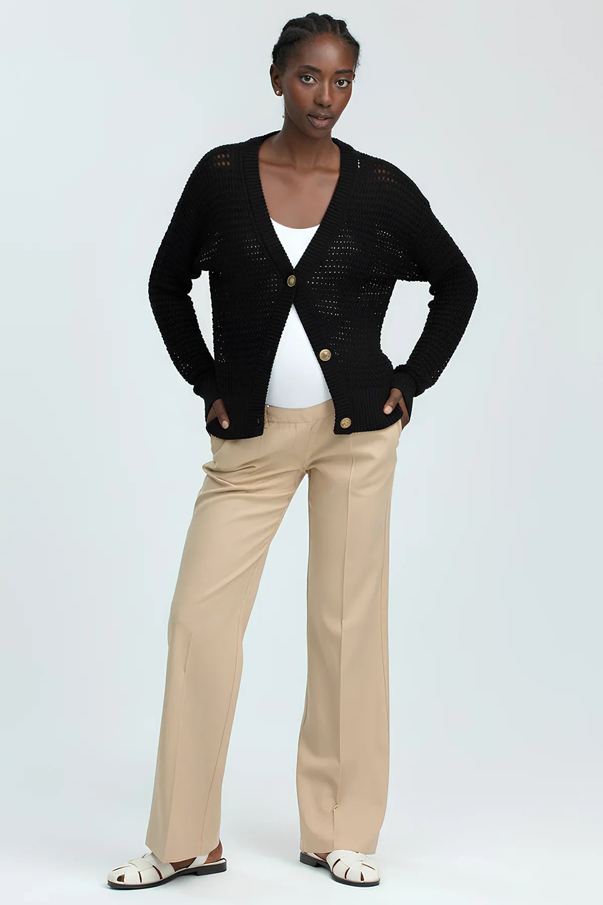 Donna che indossa cardigan nero e pantaloni beige premaman eleganti, moda premaman