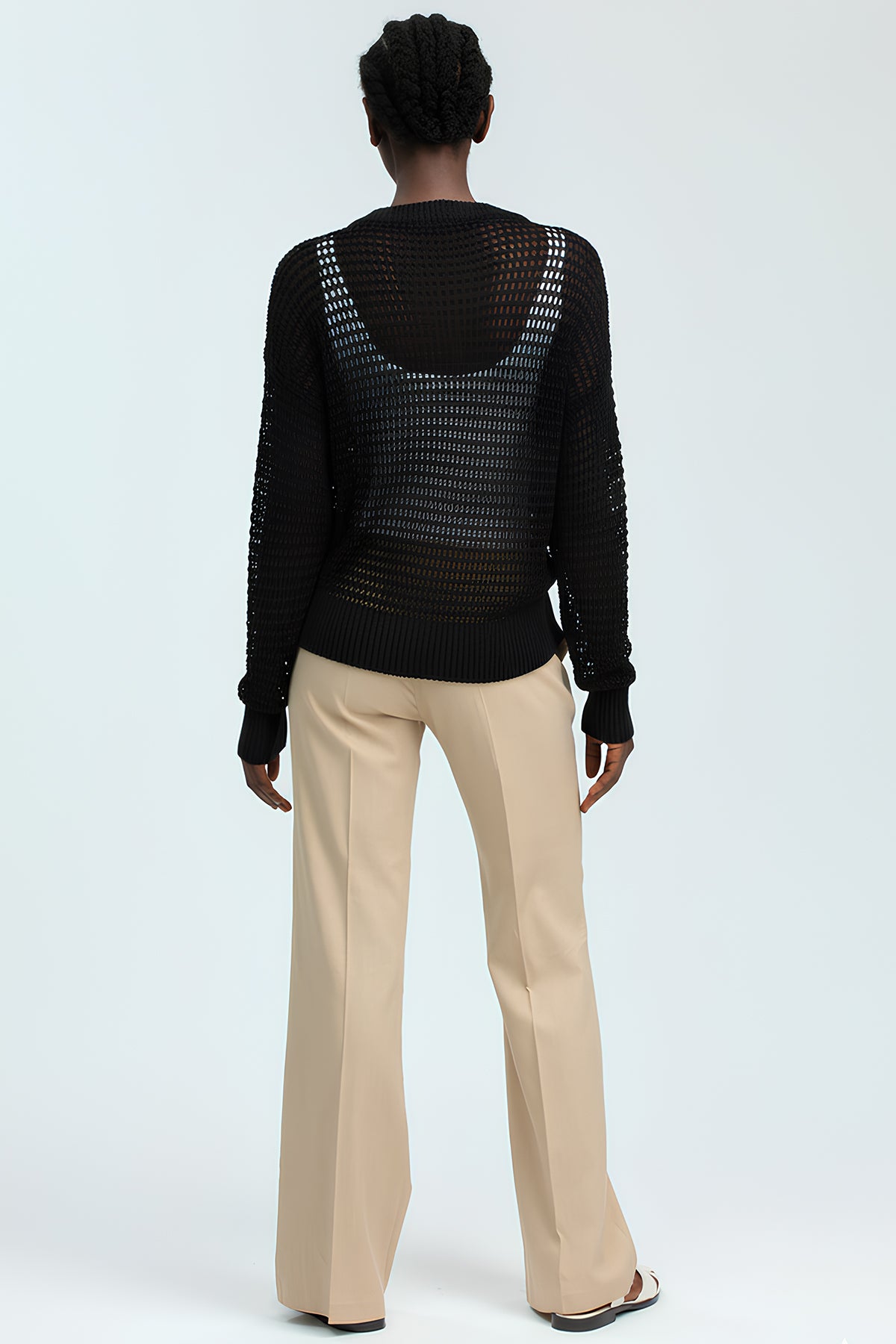 Donna di spalle con maglione nero traforato e pantaloni premaman beige eleganti