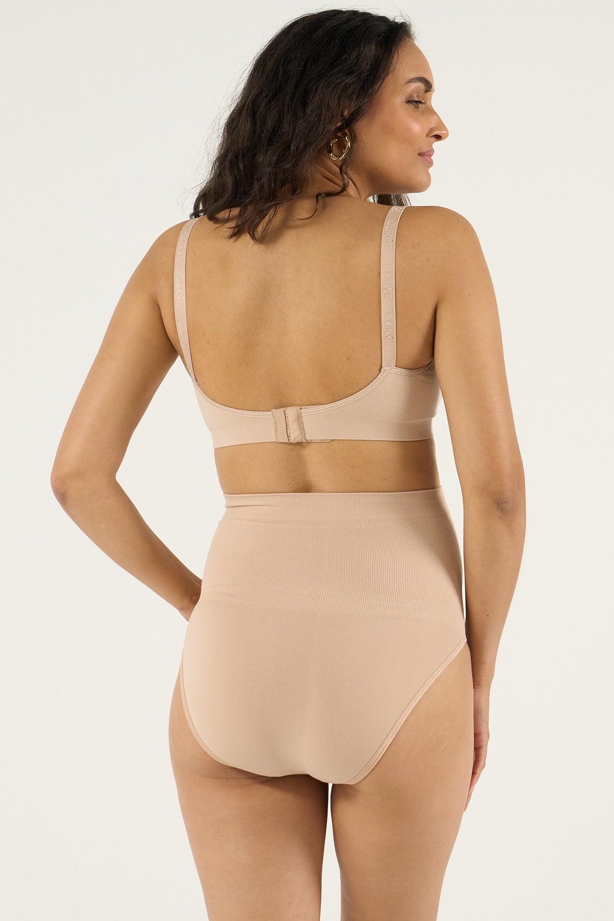 Donna indossa intimo premaman nude, slip e reggiseno elasticizzati per gravidanza