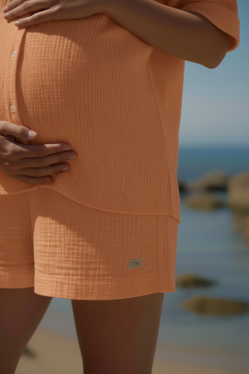 Donna incinta con set premaman arancione in tessuto leggero sulla spiaggia