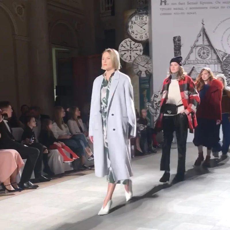 Modella sfilata con cappotto premaman grigio chiaro e abito premaman stampato.