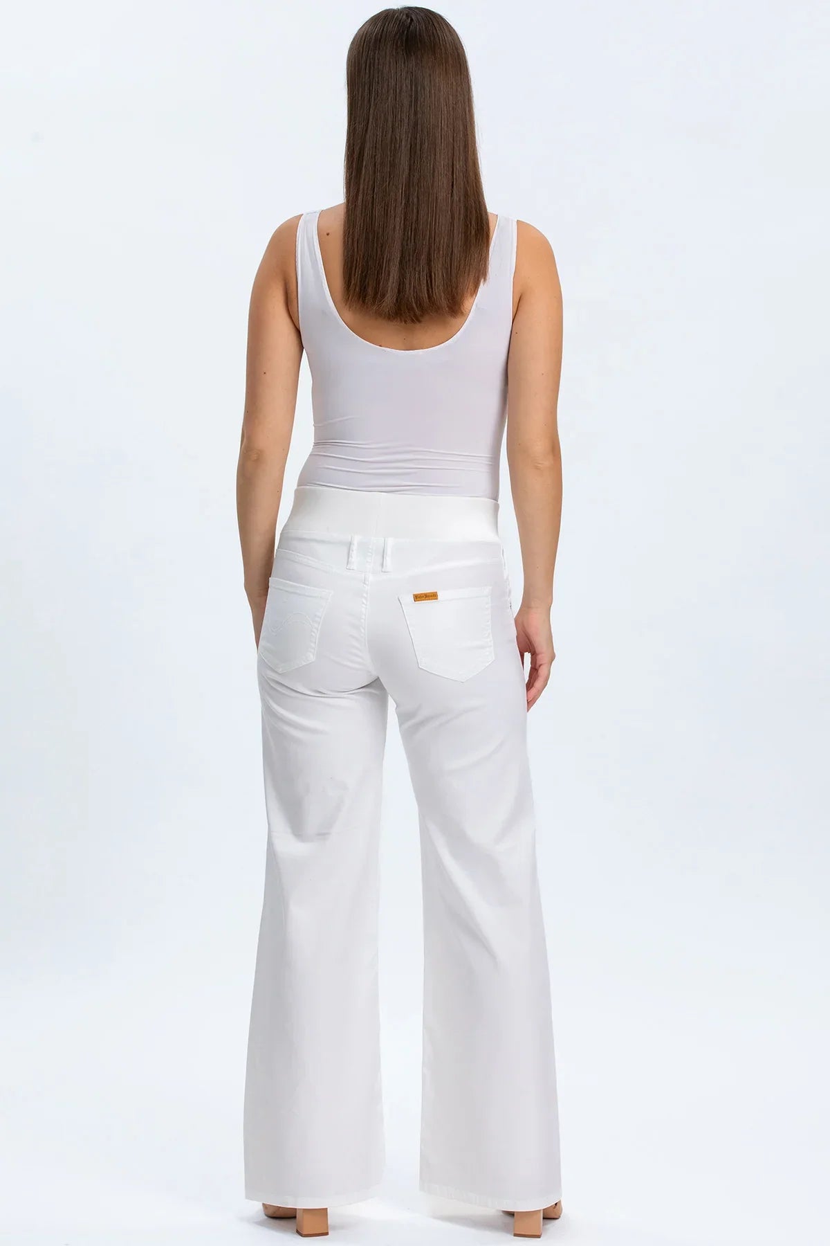 Pantaloni premaman bianchi a zampa con fascia elasticizzata in vita, indossati da donna di spalle