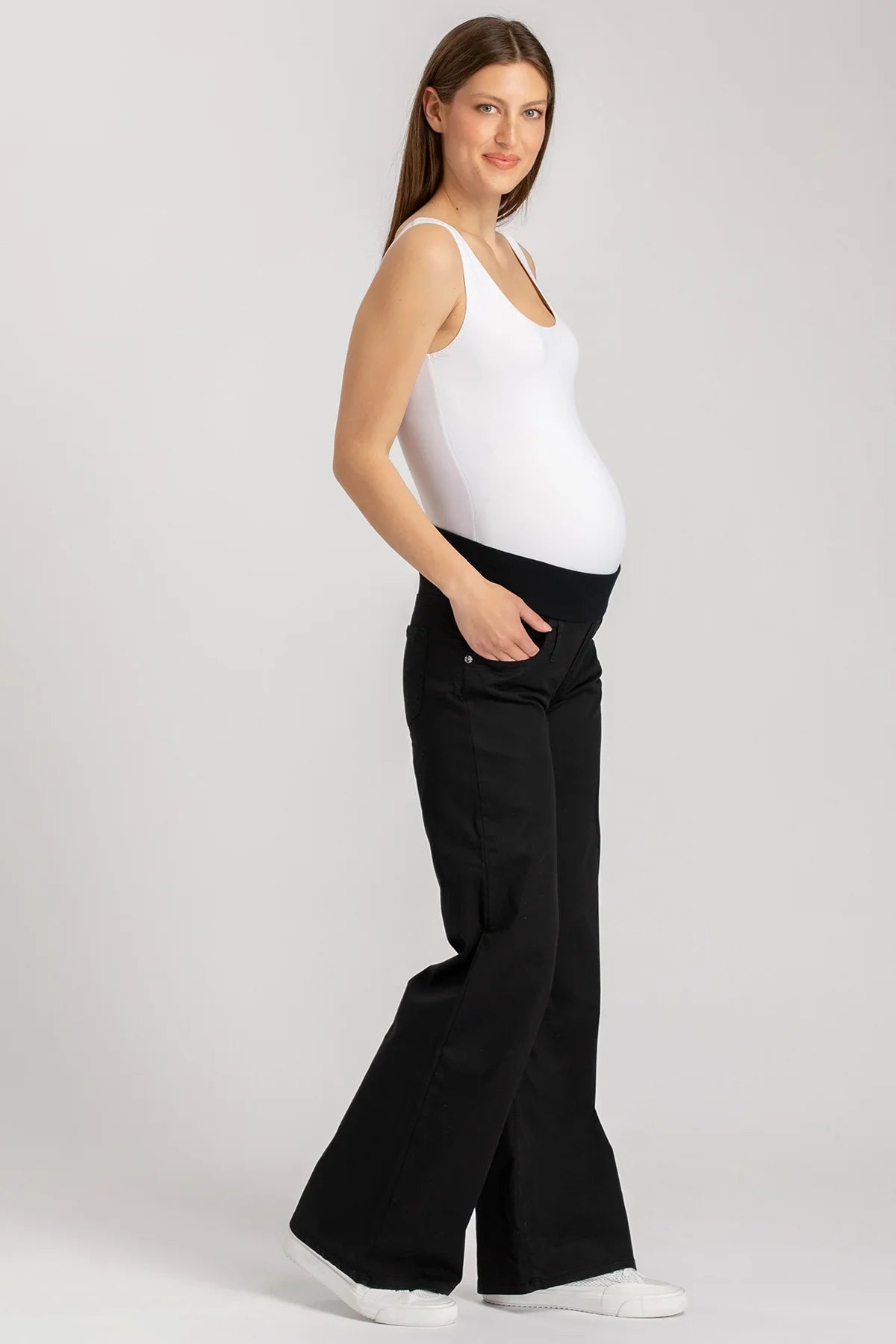 Donna incinta indossa pantaloni premaman neri con fascia elastica e canotta bianca