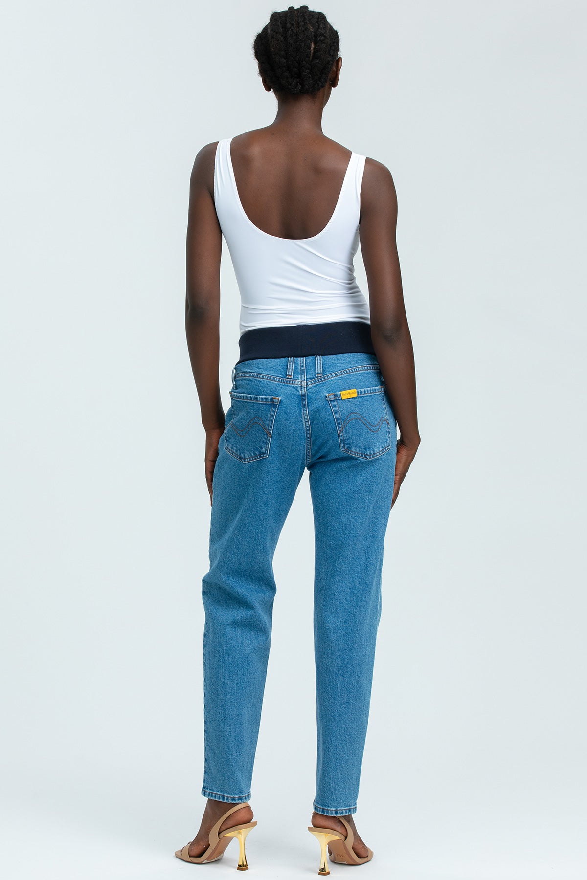 Jeans premaman tapered a vita alta con fascia elastica, indossati da donna su sfondo neutro.
