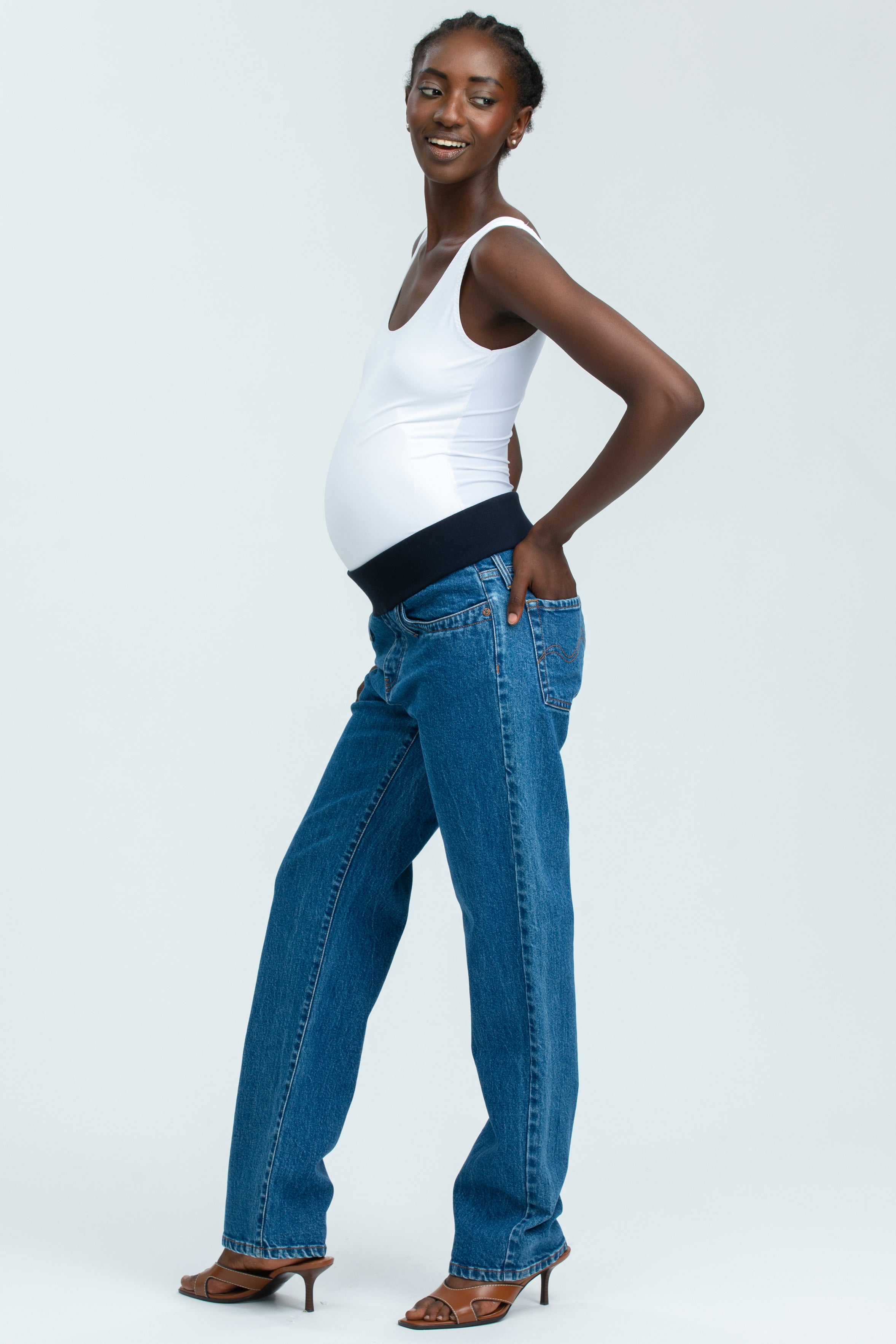 Modella incinta indossa jeans premaman regular straight e canotta bianca, abbigliamento premaman