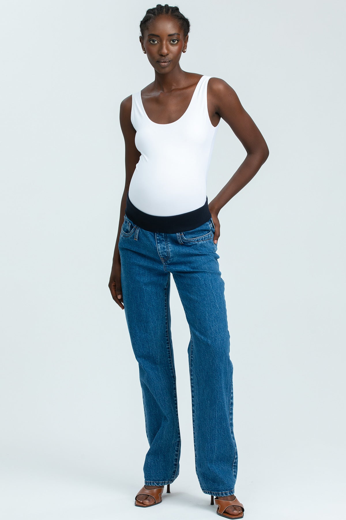Modella indossa jeans premaman dritti a vita alta con fascia elastica e top bianco, abbigliamento premaman elegante.