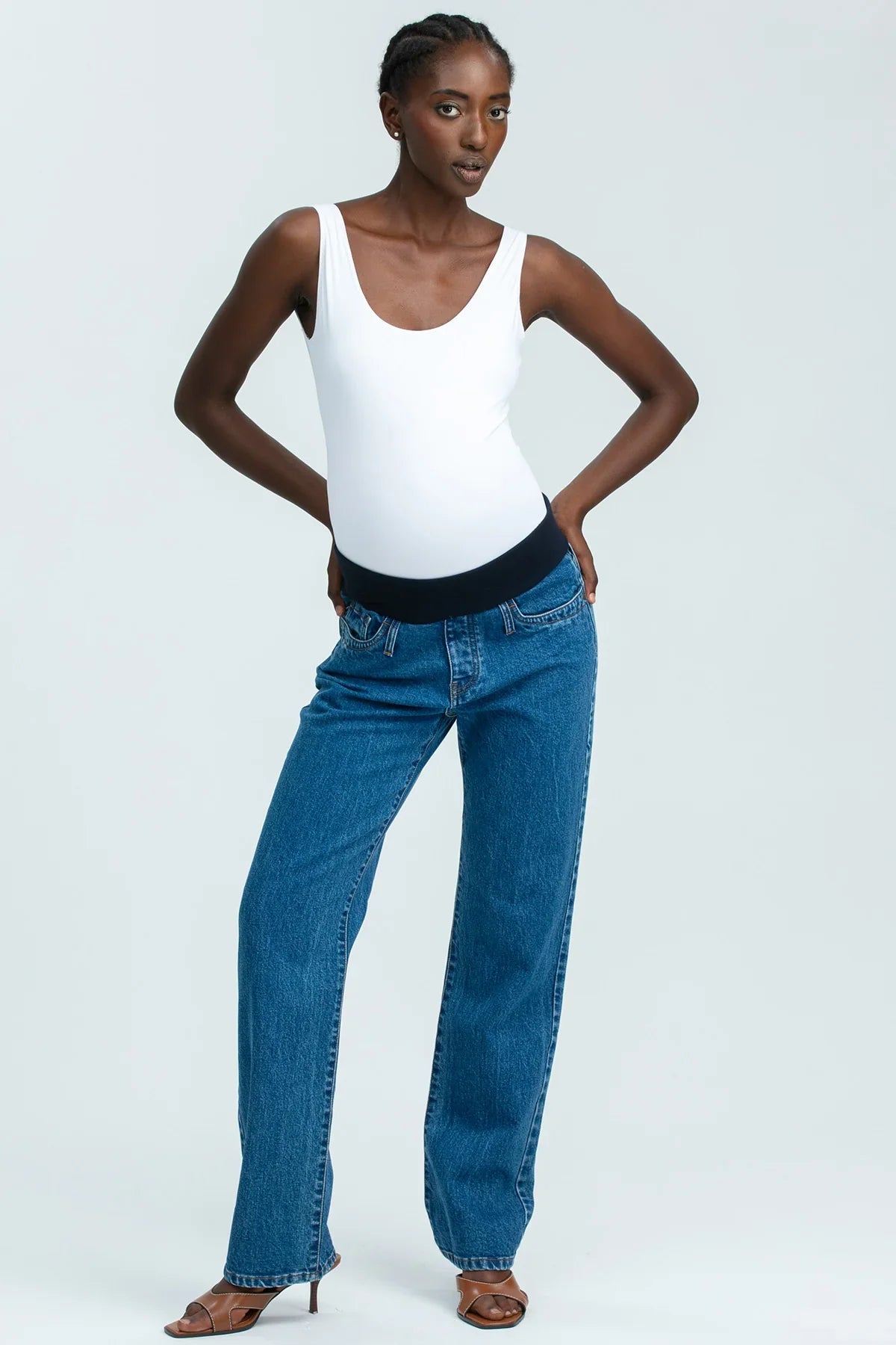 Modella indossa jeans premaman dritti a vita alta con fascia elastica comoda, abbigliamento premaman elegante.