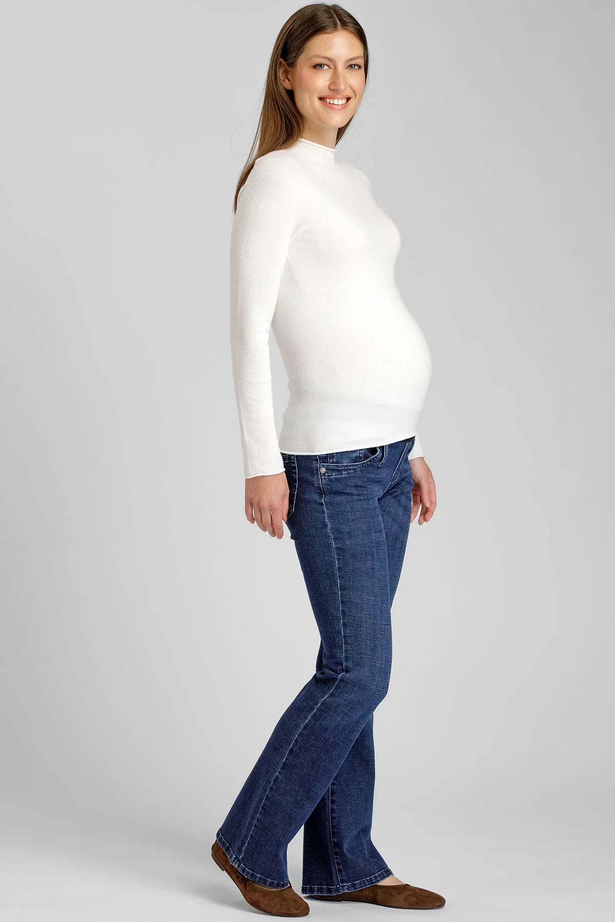 Donna che indossa una maglia premaman bianca a collo alto e jeans premaman Pietro Brunelli Maternity.