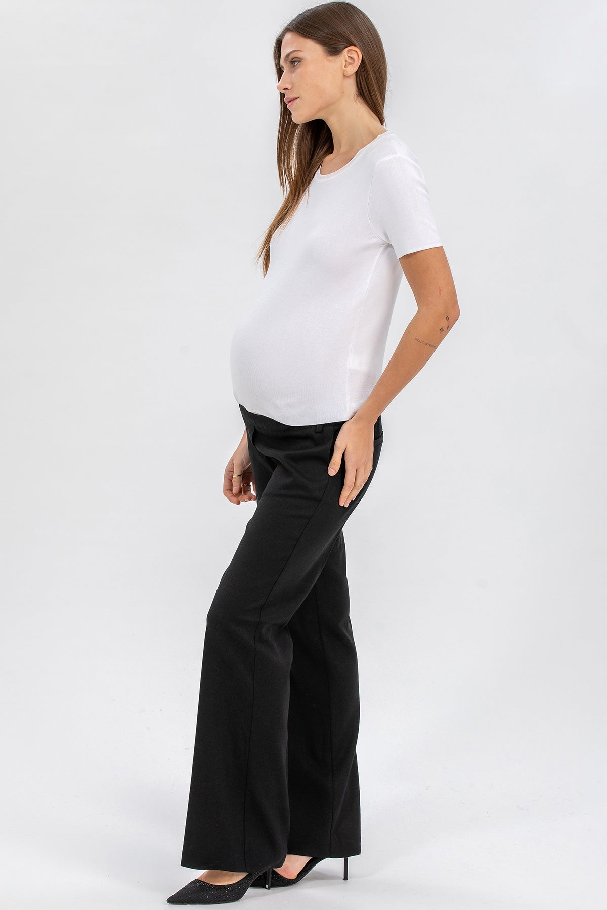 Donna incinta indossa t-shirt bianca premaman e pantaloni neri eleganti