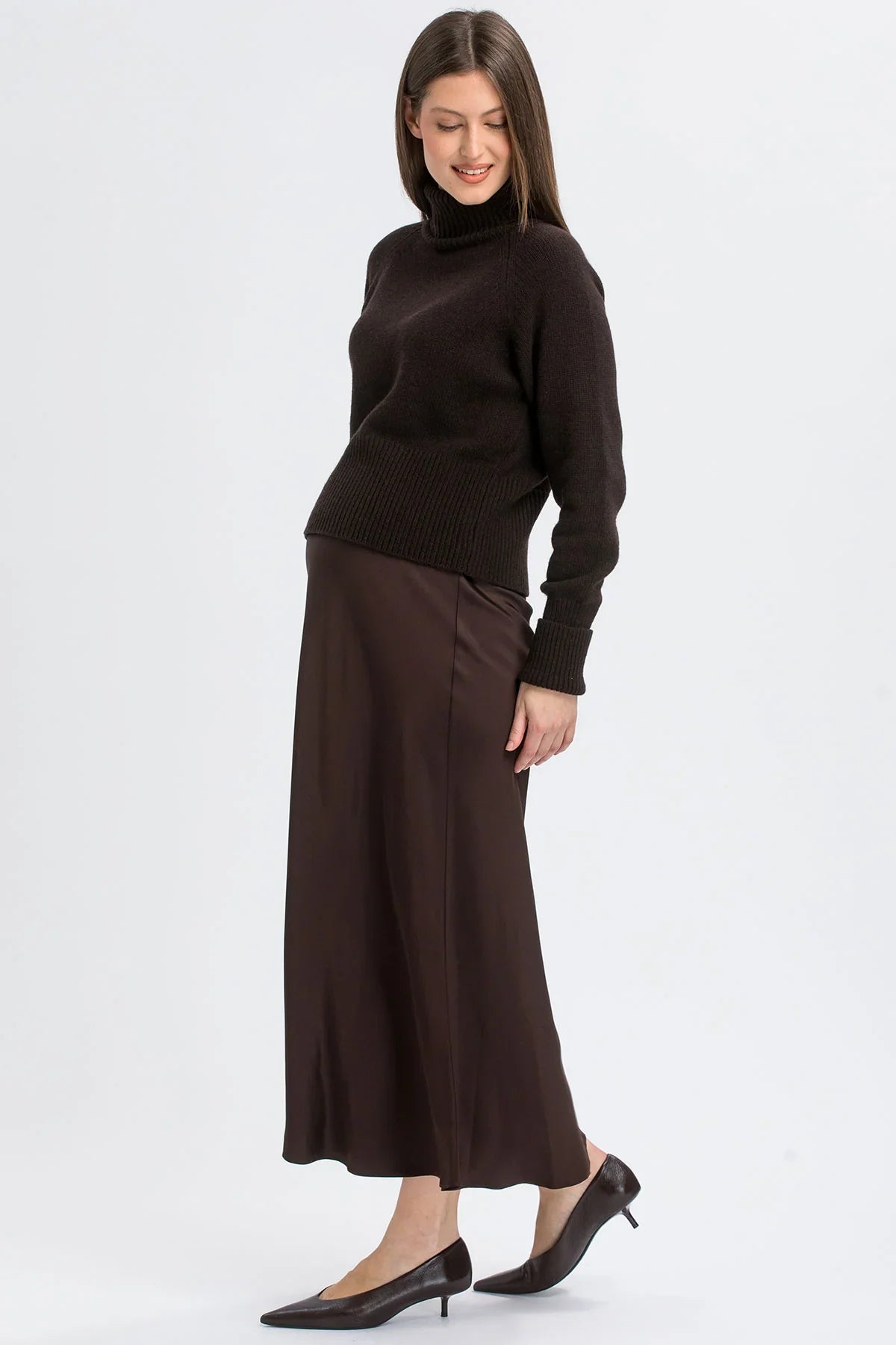 Donna con gonna premaman lunga in raso marrone e maglione a collo alto di Pietro Brunelli Maternity