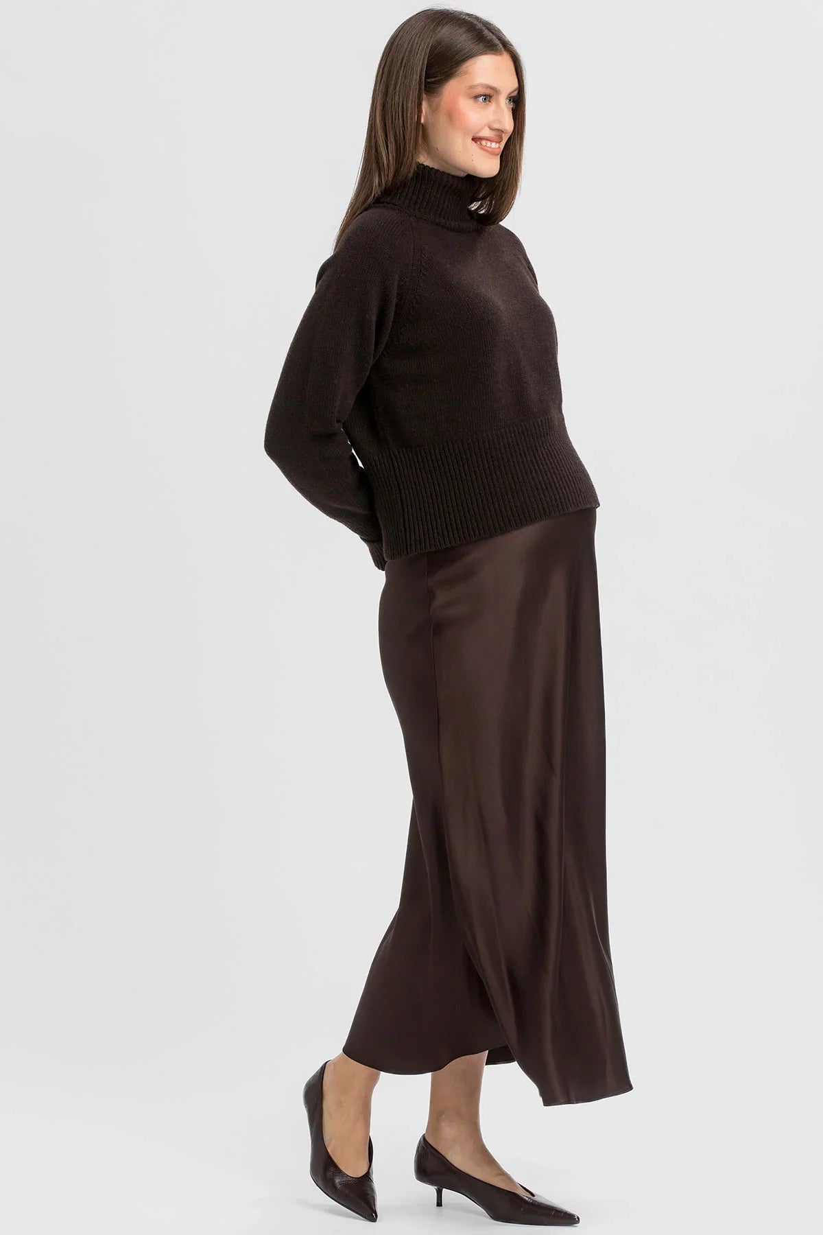 Donna che indossa una gonna premaman lunga in raso marrone di Pietro Brunelli Maternity.