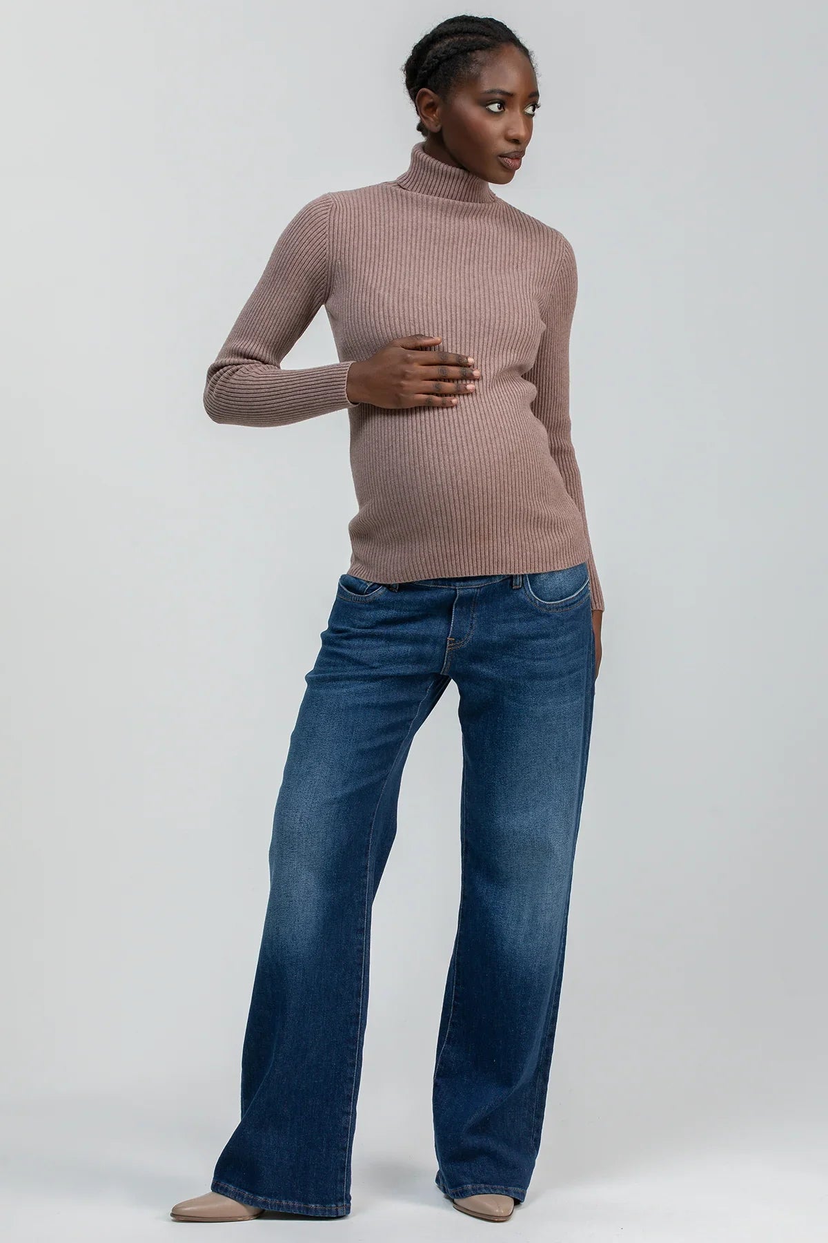 Donna incinta con maglione premaman a collo alto marrone e jeans confortevoli
