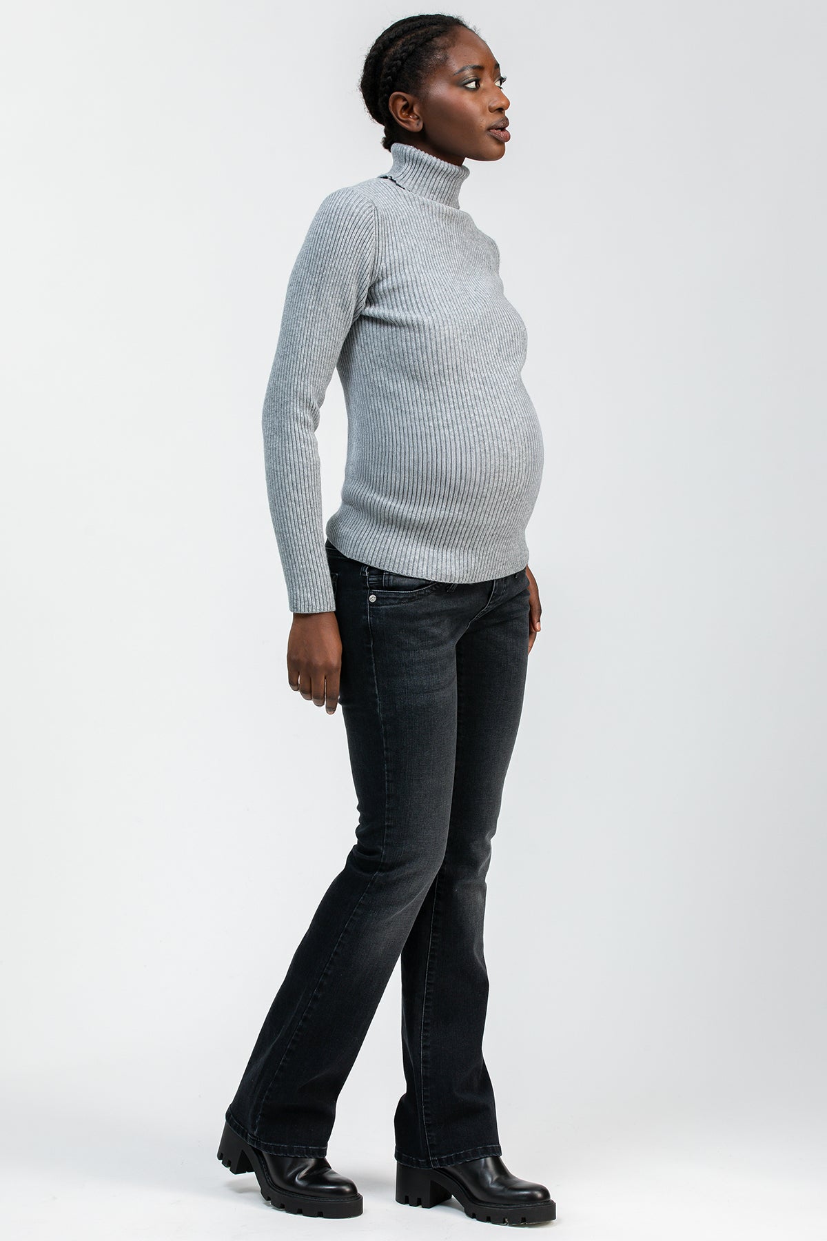 Donna incinta con maglione grigio e jeans premaman bootcut neri in posa laterale