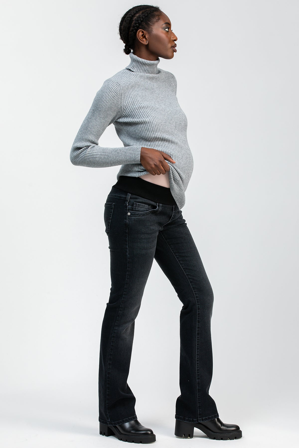 Modella premaman con jeans bootcut neri elasticizzati e maglione grigio a collo alto