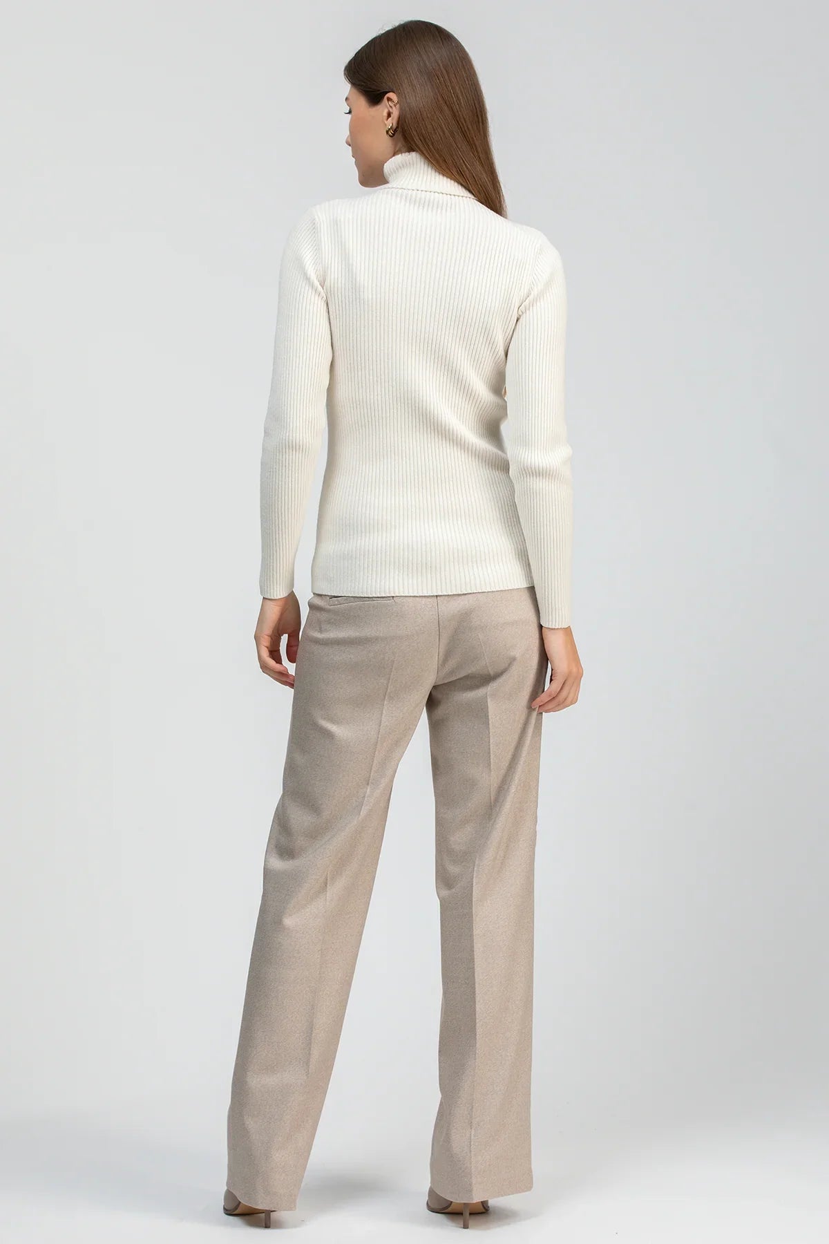 Look premaman elegante con maglia panna a collo alto e pantaloni beige dal taglio sartoriale