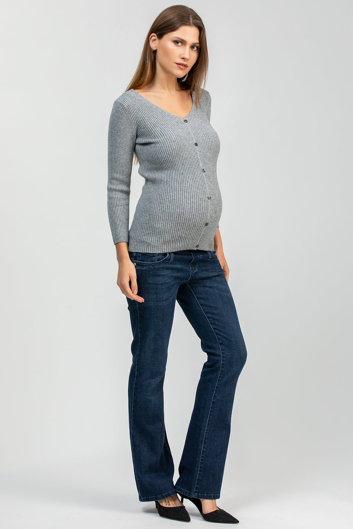 Modella incinta con maglione grigio a costine e jeans premaman svasati blu