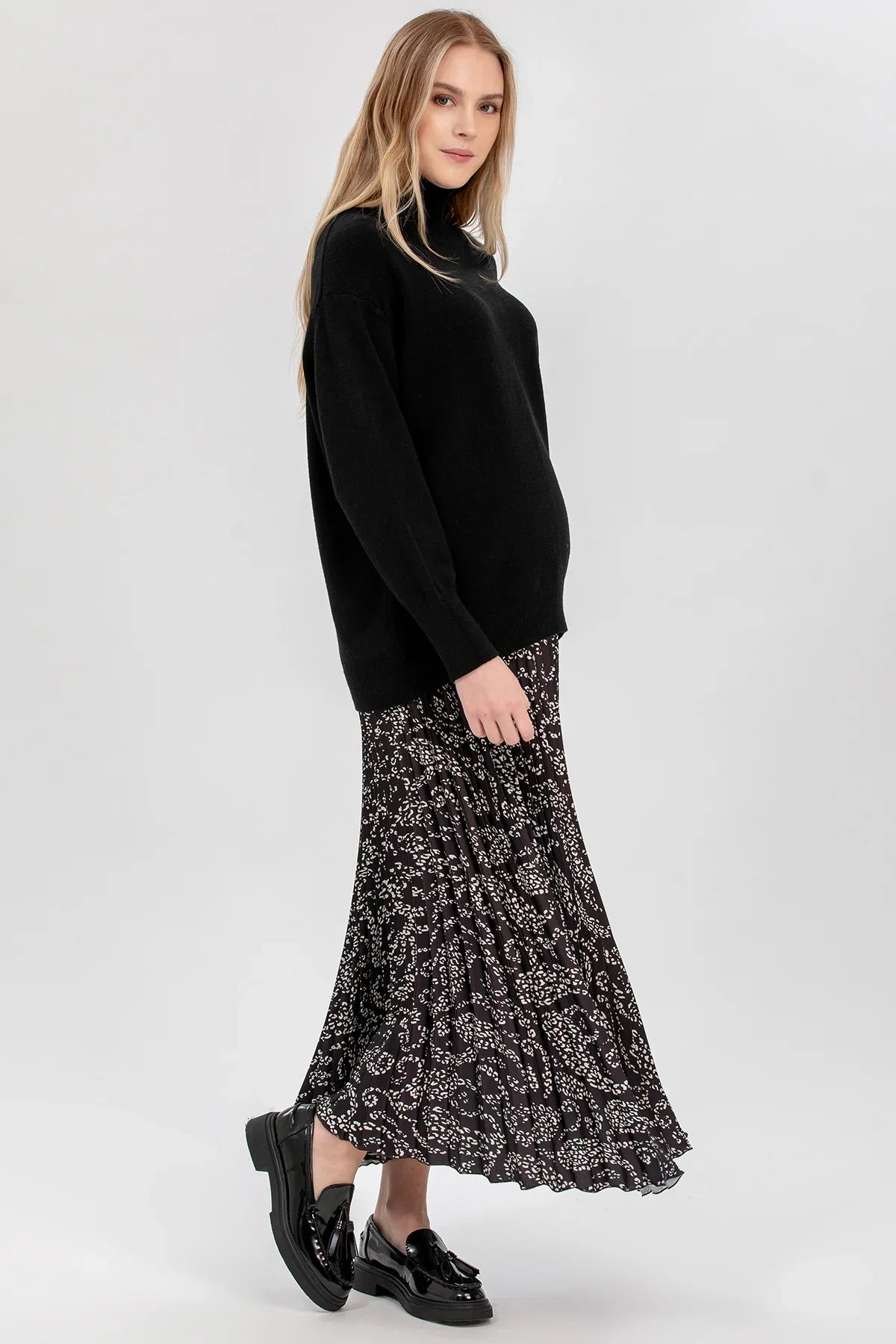 Donna con maglia premaman nera a collo a lupetto Pietro Brunelli Maternity e gonna fantasia.