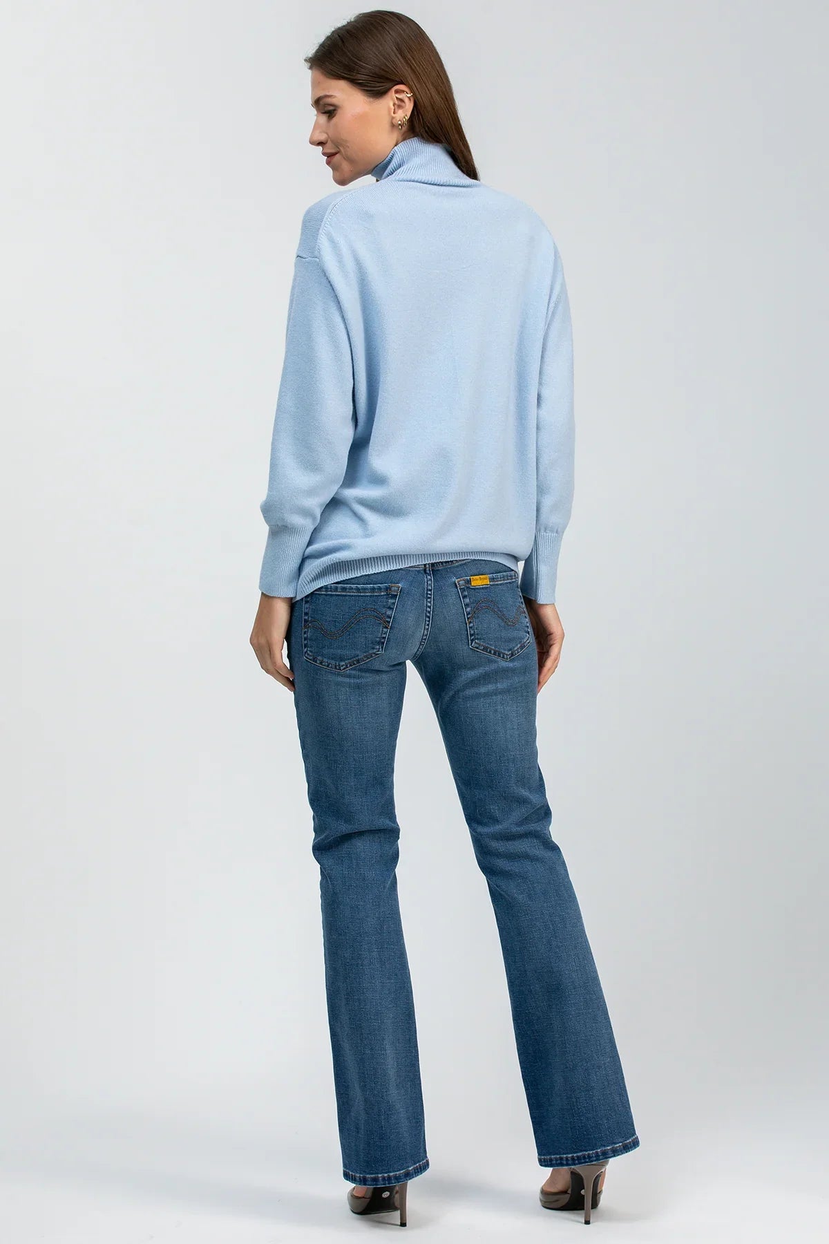 Donna di spalle con maglia premaman azzurra a collo lupetto e jeans premaman blu di Pietro Brunelli Maternity