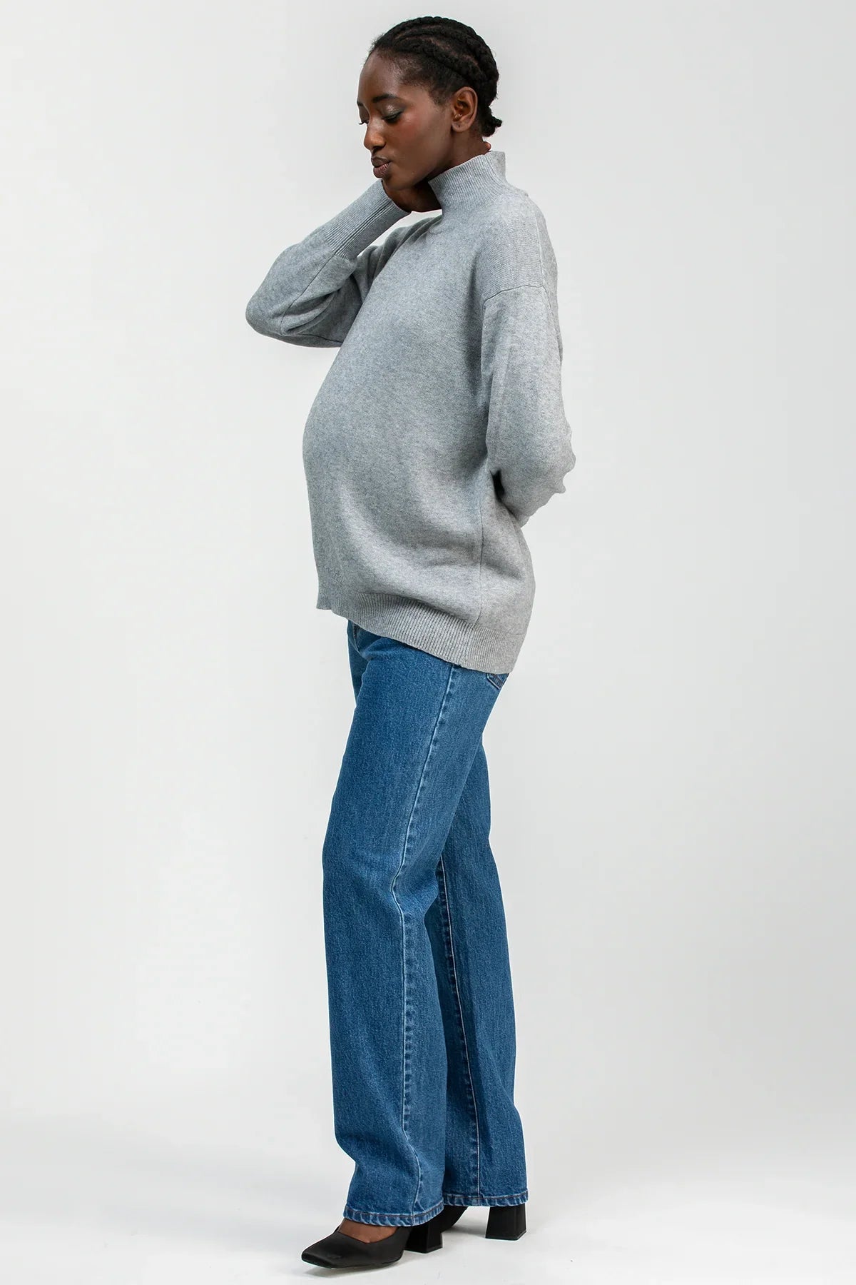 Donna che indossa maglia premaman grigia con collo a lupetto e jeans premaman Pietro Brunelli Maternity